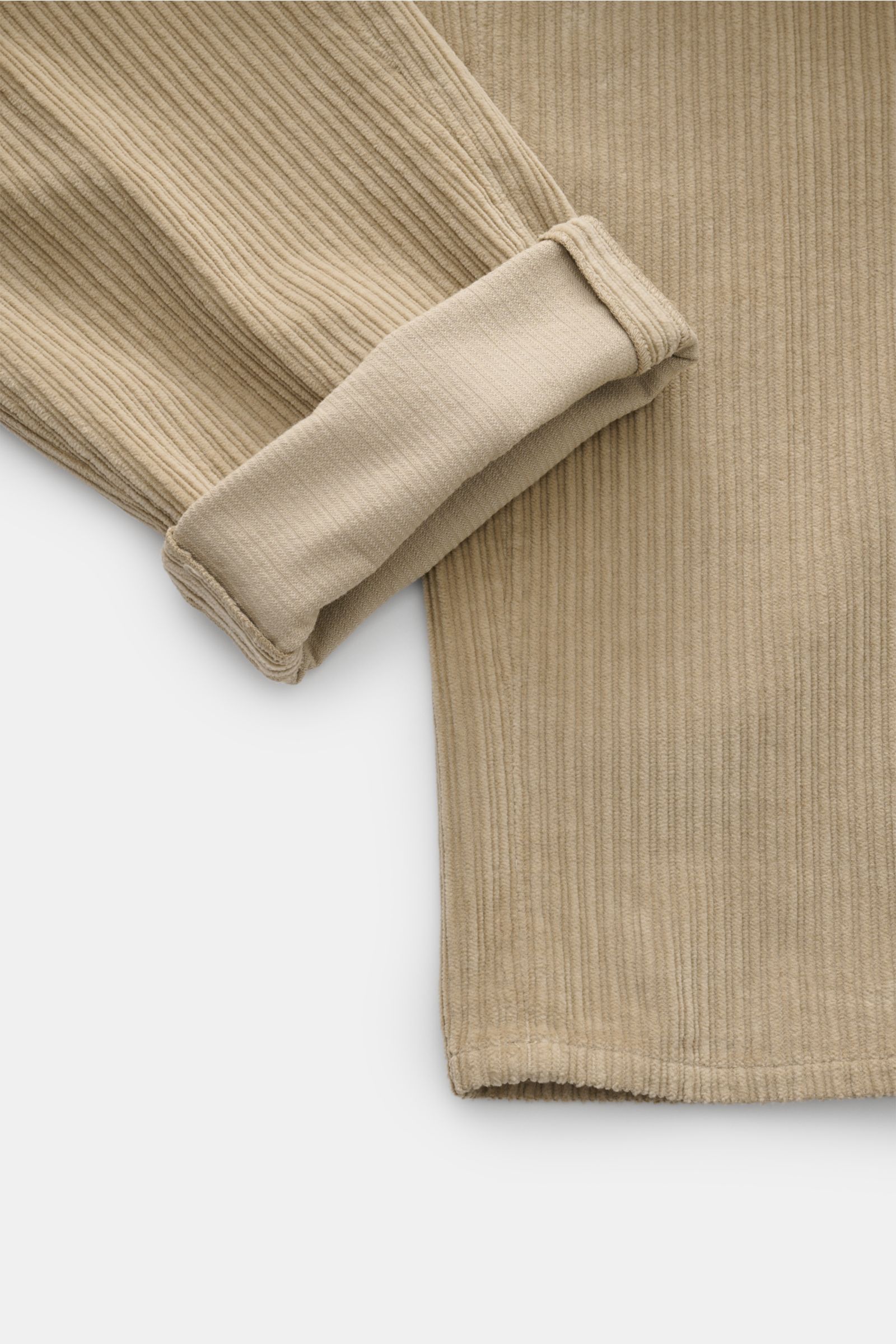 Close-up front-side view of beige GTA Cordhose 'Silvio' showing soft cotton cord fabric with a lightly elastic, soft-grip texture, regular fit, slightly tapered leg, elastic waistband insert, zipper and button closure, simple waistband pleat, French pocke
