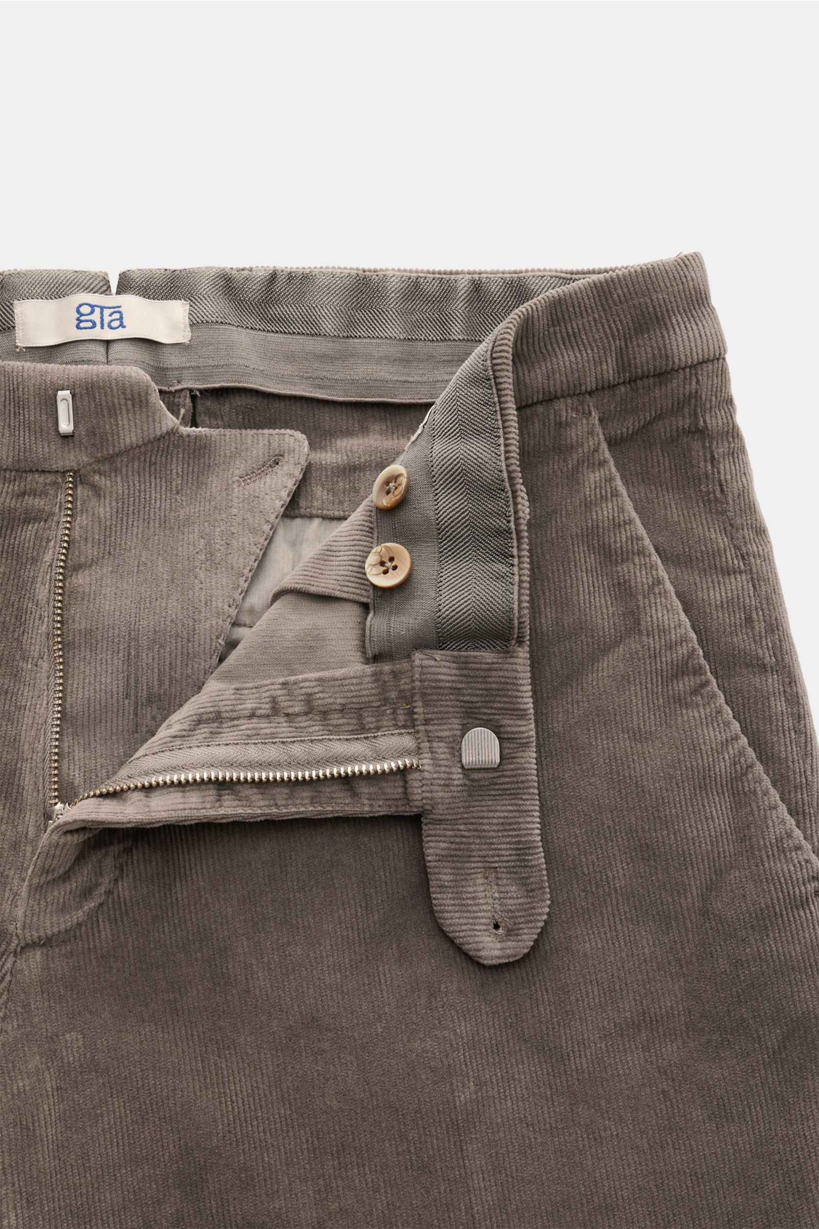 Close-up front view of GTA Corduroy trousers 'Federico' dark grey showing fine cotton and modal corduroy fabric, slim fit with slightly tapered cut, zip and waist button, waistband with elastic insert, French pockets, and jetted back pockets with button, 