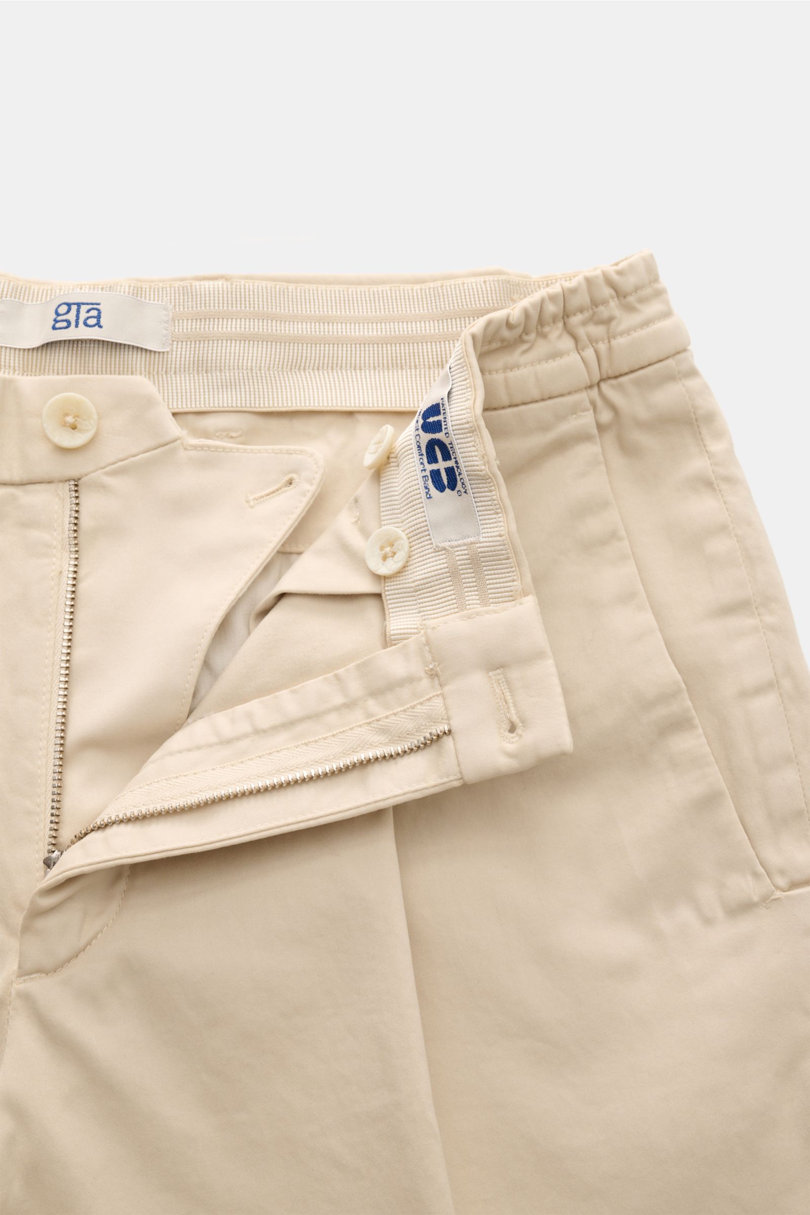 Close-up front view of GTA Cotton trousers 'Dennis' sand showing the partially elasticated waistband, zip, buttons, and soft tapered cotton fabric.