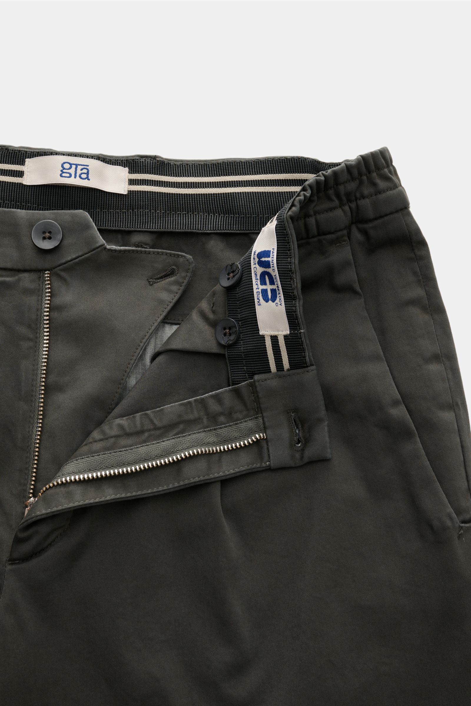 GTA Cotton trousers 'Dennis' dark grey shown from top close-up of waistband and zipper, featuring elasticated waistband, zip, buttons, and soft cotton fabric. 

The cotton trousers 'Dennis' by GTA are defined by their soft feel and feature an elasticat
