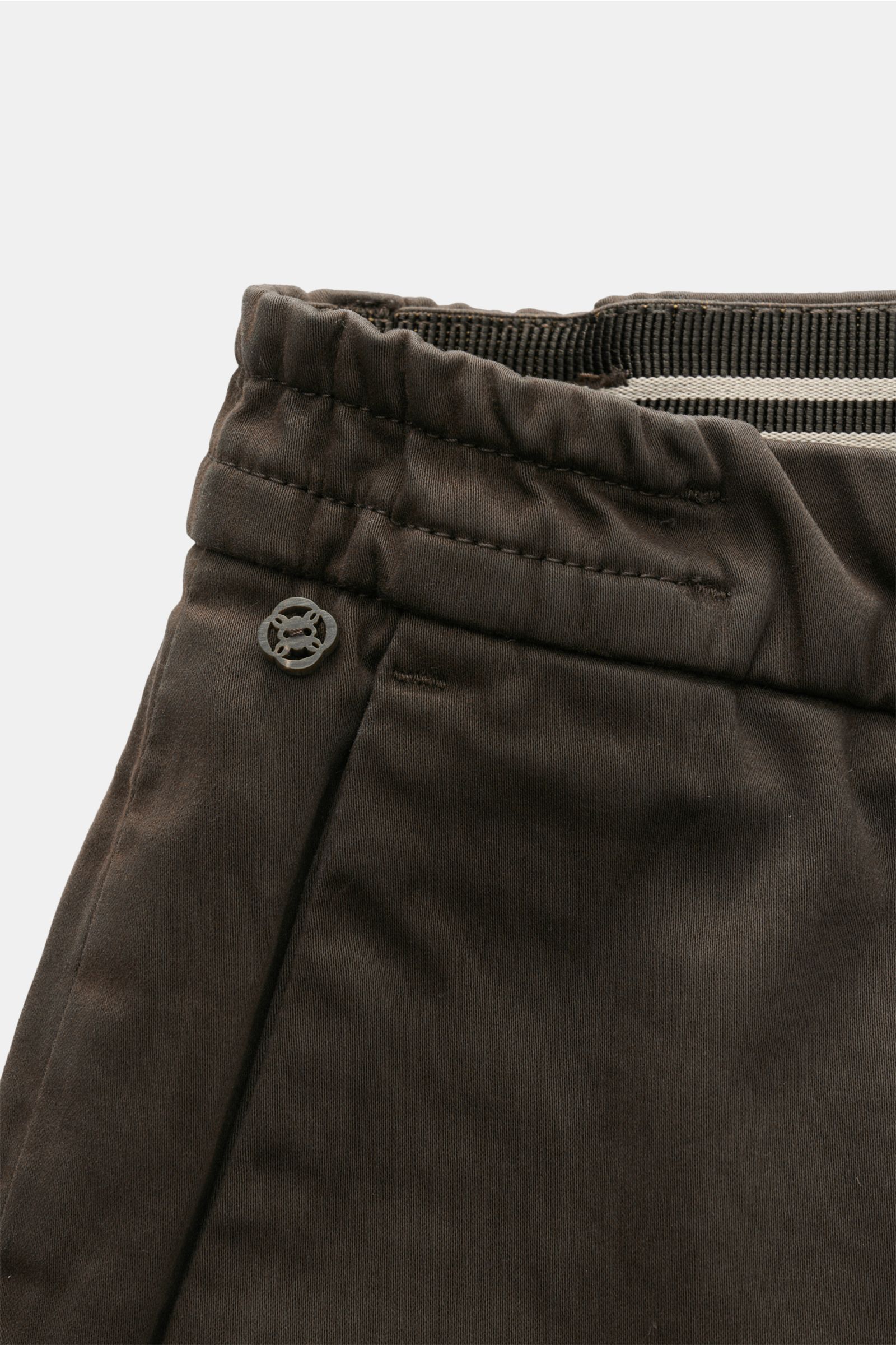 GTA Cotton trousers 'Dennis' dark brown shown in close-up from the front top perspective, featuring a partially elasticated waistband with soft, slightly elasticated cotton, zip and waist buttons, French pockets, small logo detail, tapered fit, regular th