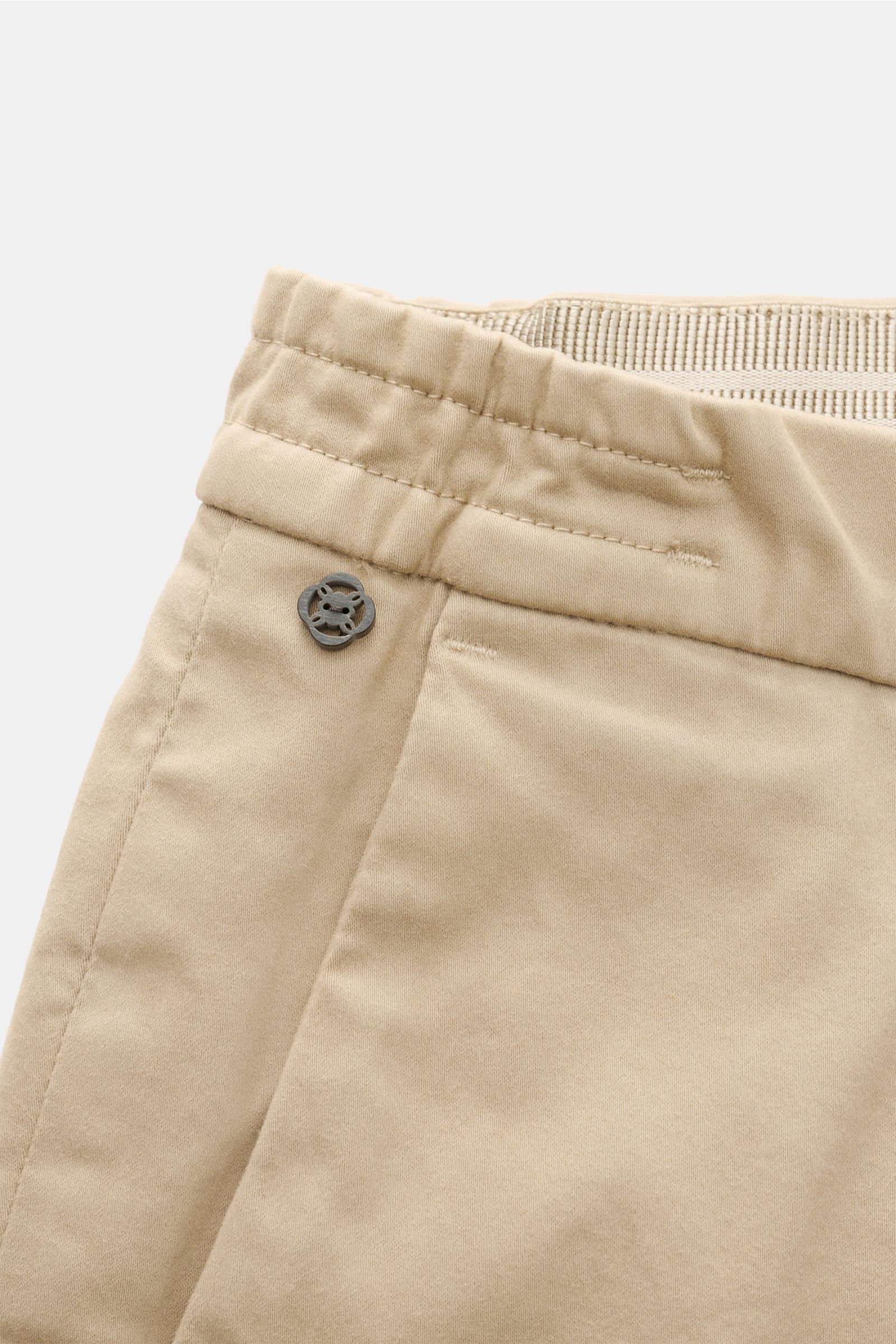 GTA Baumwollhose 'Dennis' beige in Nahaufnahme von oben, weiche, leicht elastische Baumwolle, teilelastischer Bund, kleines Logo-Detail sichtbar.