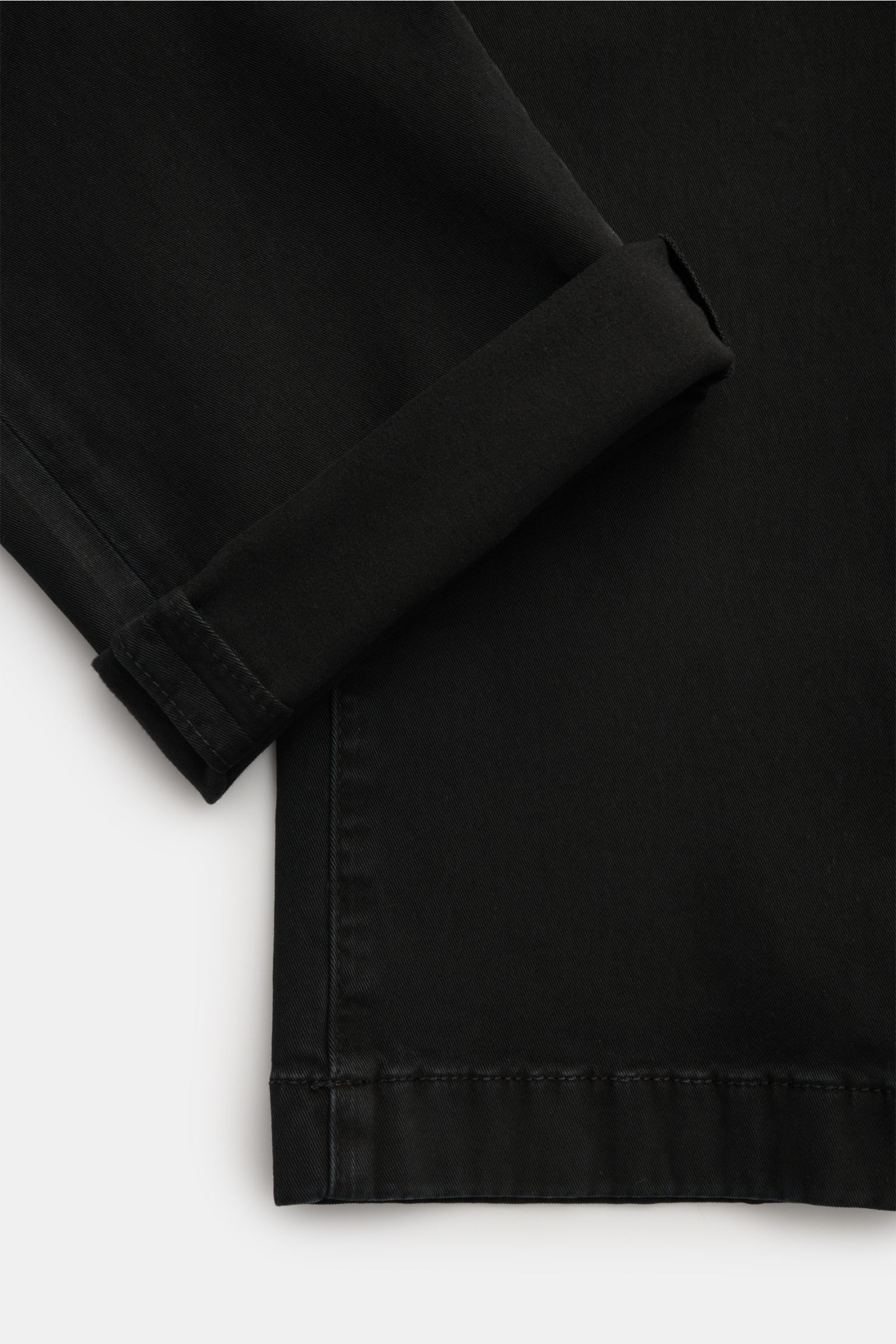 Close-up, top-down view of the hem and cuff of the Jacob Cohen Chino 'Bobby' schwarz, made of soft cotton twill with a slim fit, garment dyed, featuring a small velour leather patch. Präzise, italienische Handwerkskunst - dafür steht das Label JACOB COHEN