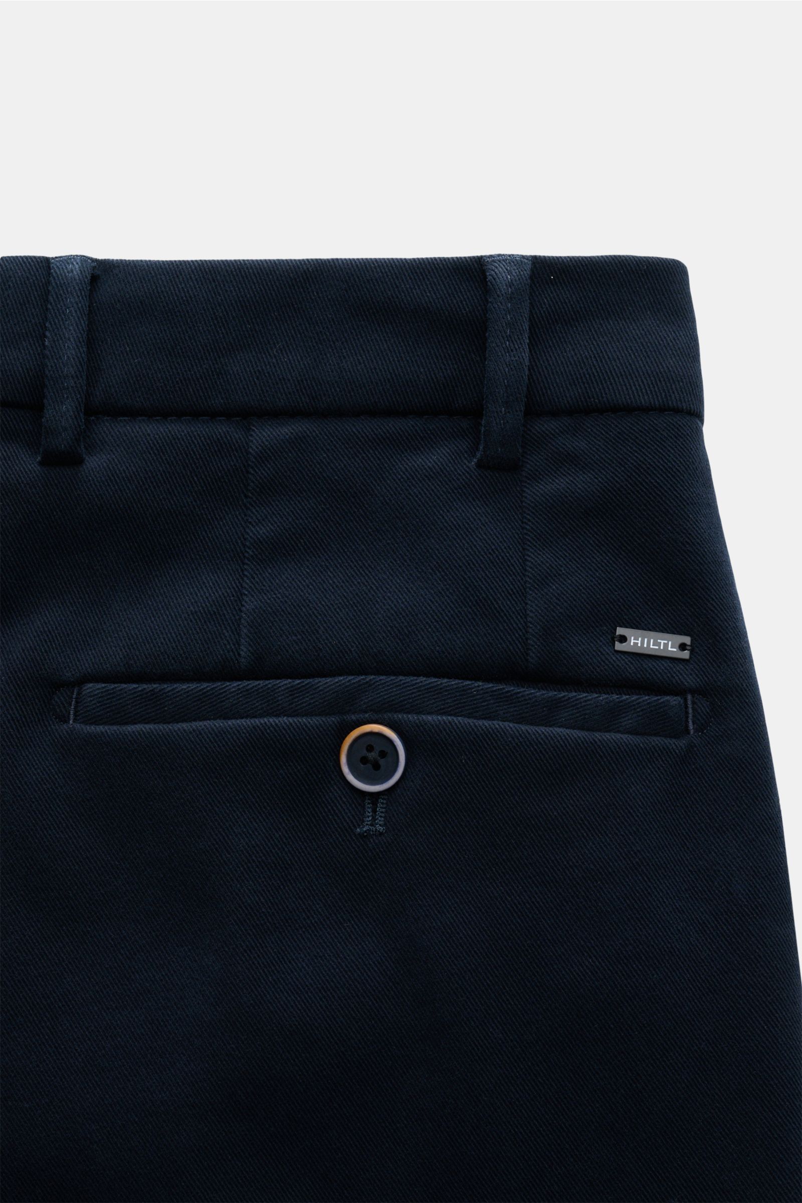 Nahaufnahme der Rückseite der Hiltl Baumwollhose 'Parma' navy im Slim Fit mit paspelierten Gesäßtaschen, Knopf, Bund und Hiltl-Logo.