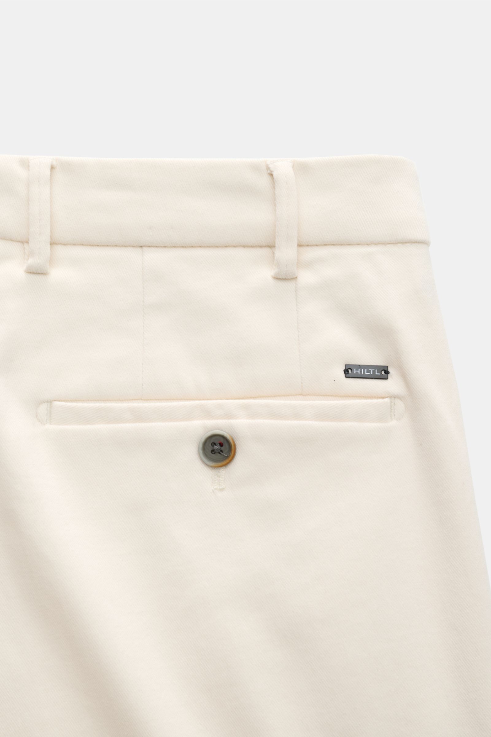 Hiltl Baumwollhose 'Parma' creme in Slim Fit, schmal zulaufend, Detailaufnahme der paspelierten Gesäßtasche mit Knopf und Label.