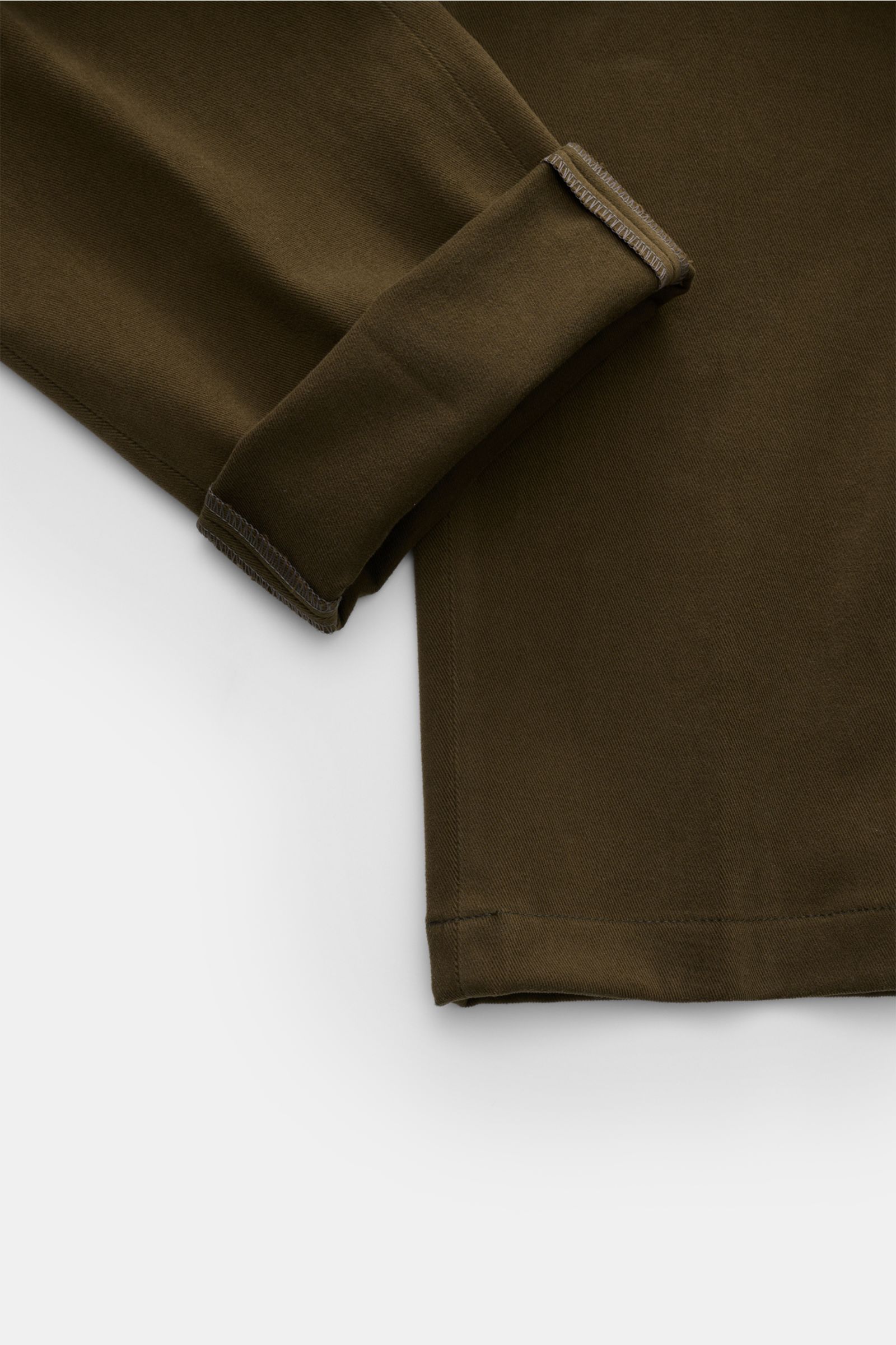 Nahaufnahme der dunkelolivfarbenen Hiltl Baumwollhose 'Parma' mit aufgerolltem Beinabschluss, elastischer Baumwolle und feiner Slim-Fit-Form.