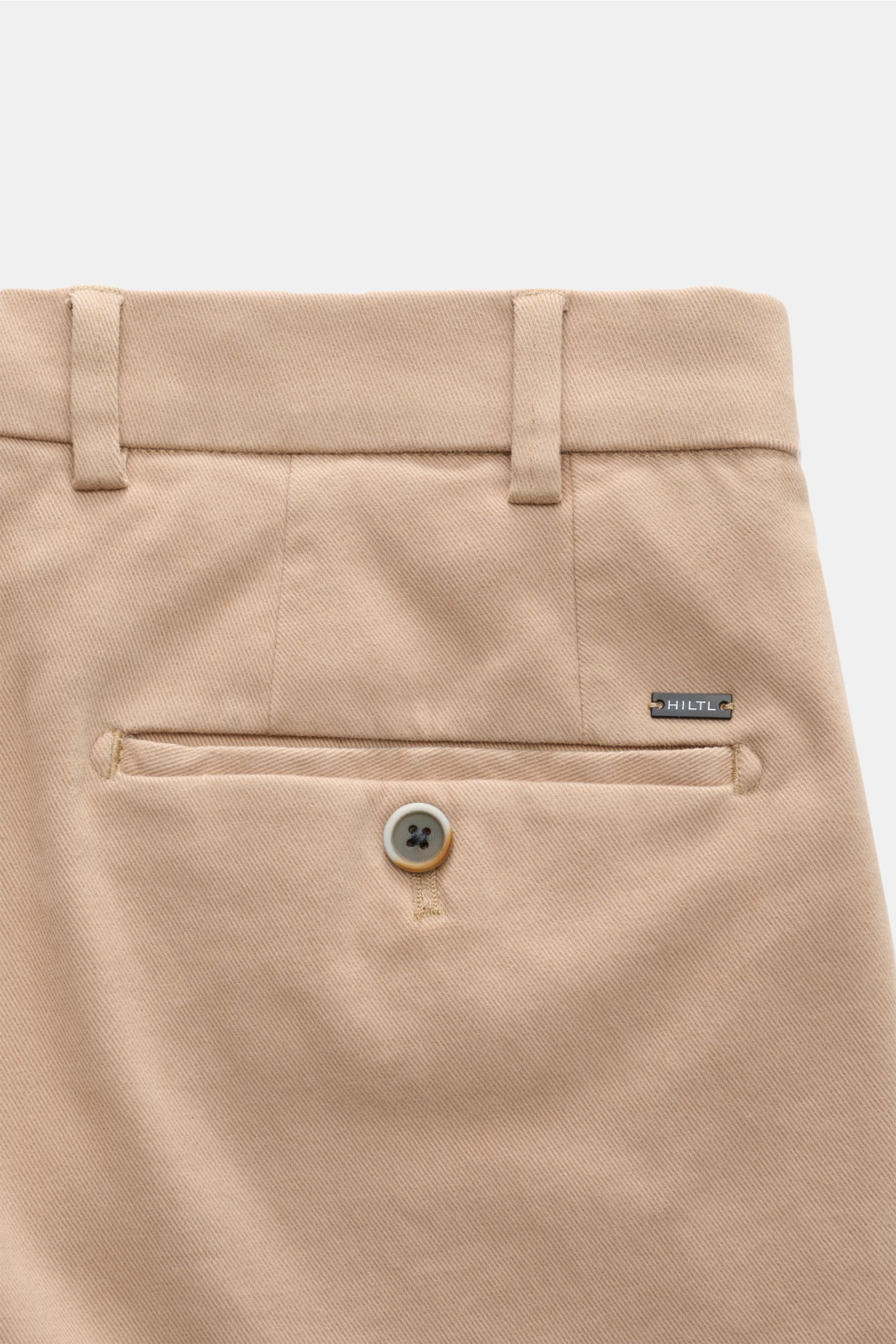 Close-up back view of Hiltl Baumwollhose 'Parma' sand, showcasing elastic cotton fabric, slim fit, soft touch, slightly tapered design, with a buttoned welt pocket and belt loops. Vielseitiges Essential: Die Baumwollhose von HILTL im Chino-Stil überzeugt 