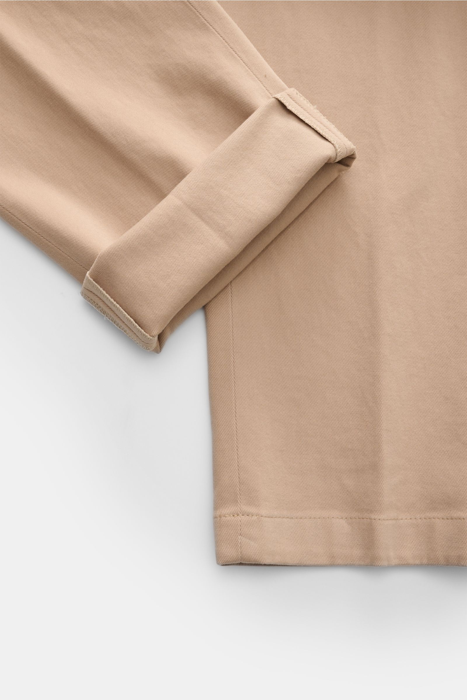 Close-up front view of the cuff and lower leg of the Hiltl Baumwollhose 'Parma' sand, a slim fit, elastic cotton chino with soft texture, zipper, button, French pockets, and welted back pockets with buttons. Versatile essential for elegant office or refin