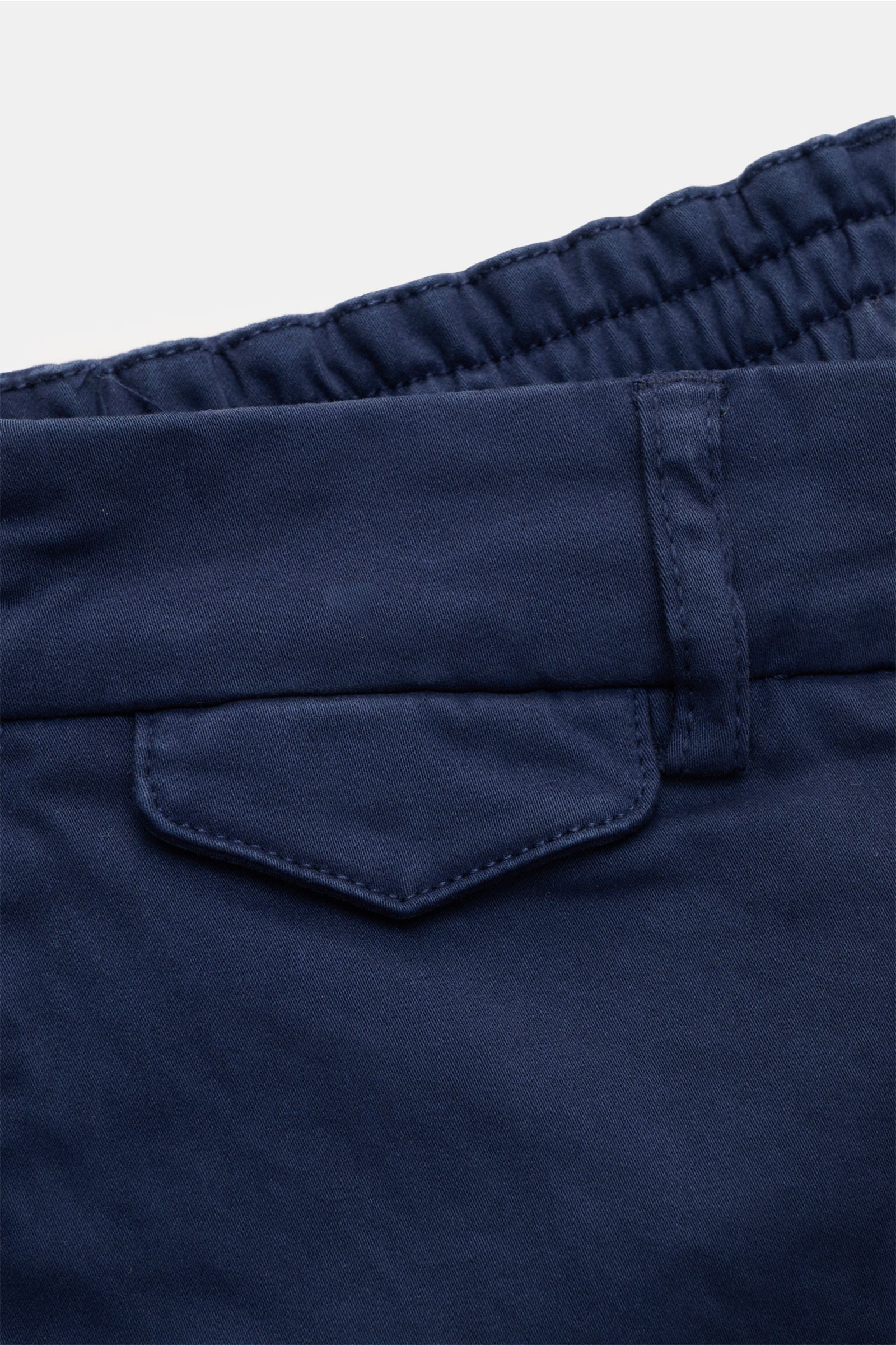 Close-up rear view of navy 04651/ A trip in a bag Cotton trousers 'Flex' showing partially elasticated waistband, button flap back pocket, and belt loop. Modern fit for everyday looks: The comfortable cotton trousers 'Flex' by 04651/ A TRIP IN A BAG with 