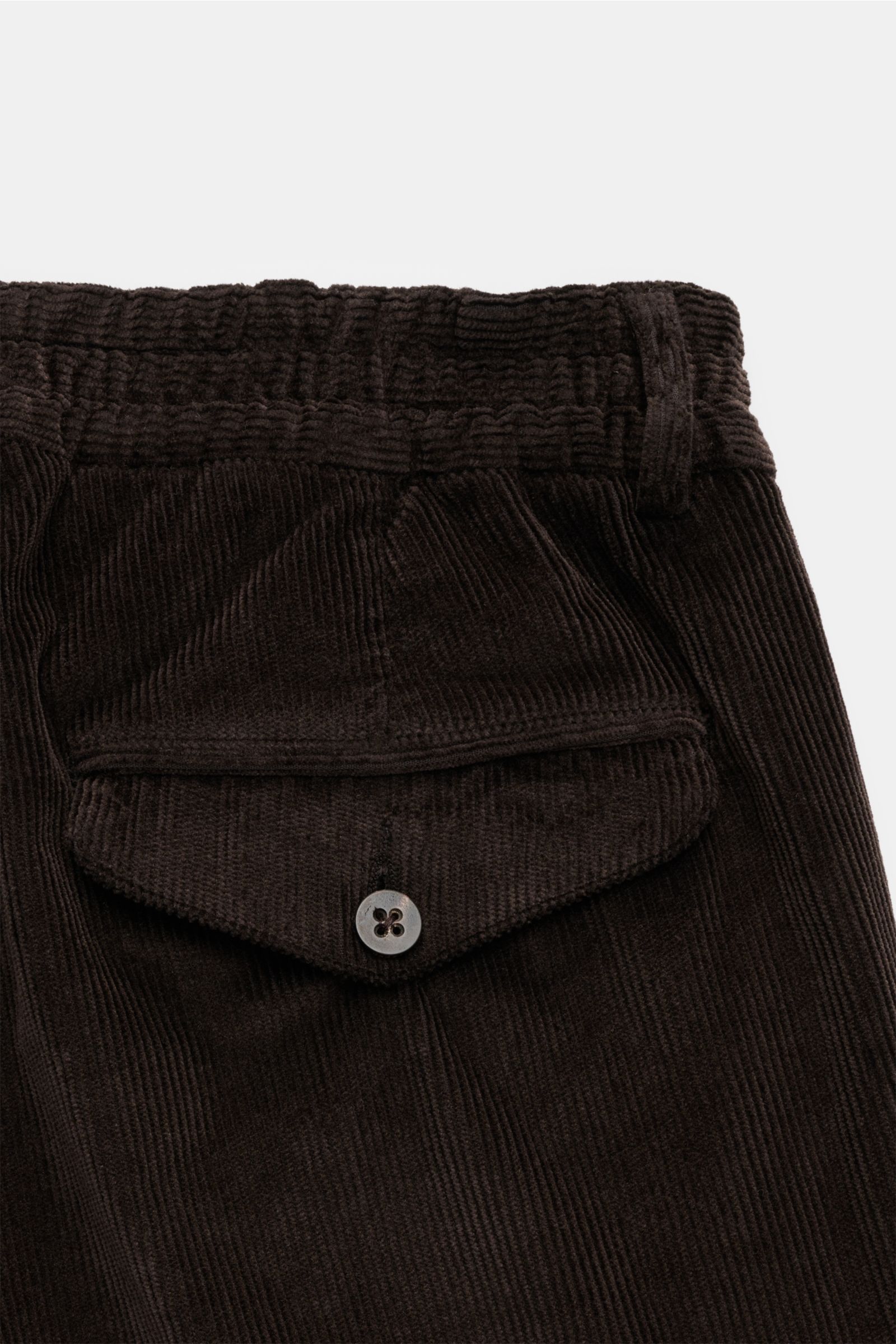 Close-up rear view of 04651/ A trip in a bag Cordhose dunkelbraun, garment dyed dark brown cotton-modal corduroy pants with buttoned back flap pocket and elastic waistband.

Welcome to the Autumn Winter Collection by 04651/ A TRIP IN A BAG – inspiriert