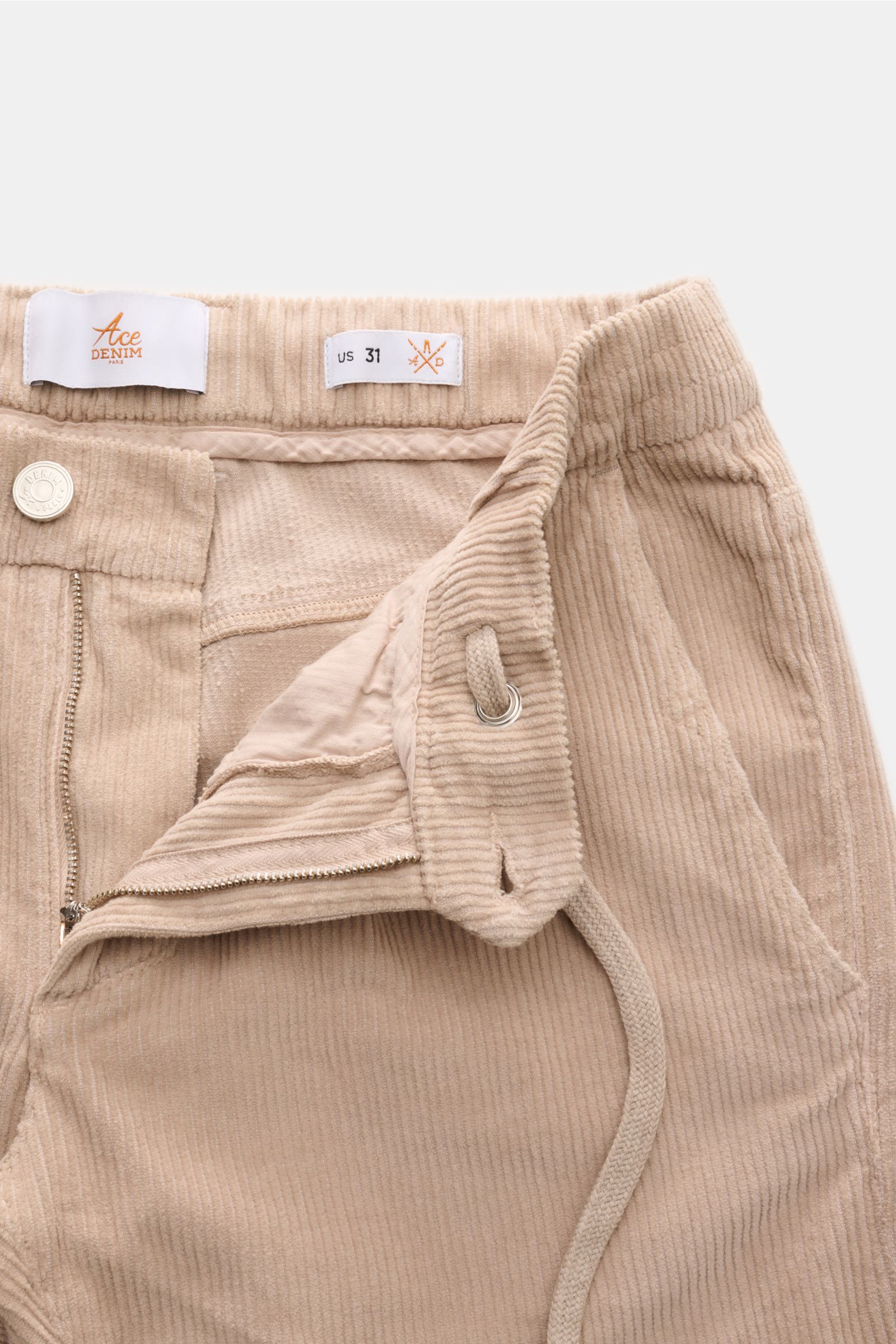 Ace Denim Cord-Jogpants beige im Close-up von oben, Slim Fit Cordhose aus reiner Baumwolle mit Reißverschluss, Bundknopf und Tunnelzug.