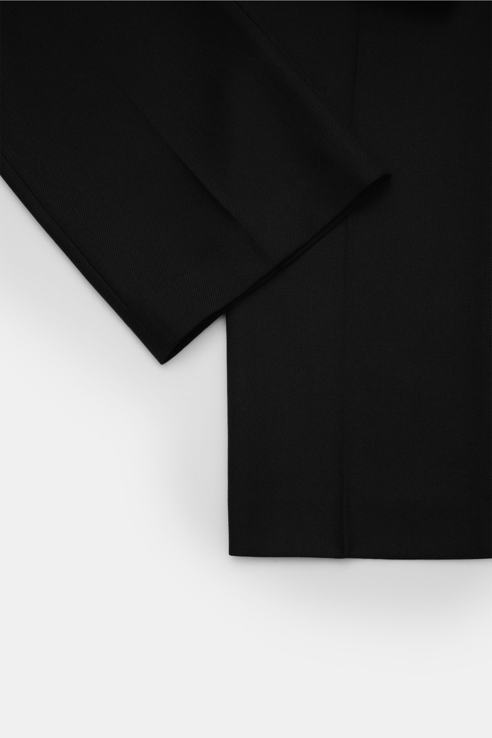 A close-up top view of the hem and lower leg section of the A.P.C. Hose 'Jim' schwarz, a stylish classic tapered fit pant. Stilvoller Klassiker: Die Hose 'Jim' von A.P.C. wird mit ihrem eleganten Design zum unverzichtbaren Essential in Ihrer Garderobe. Mi