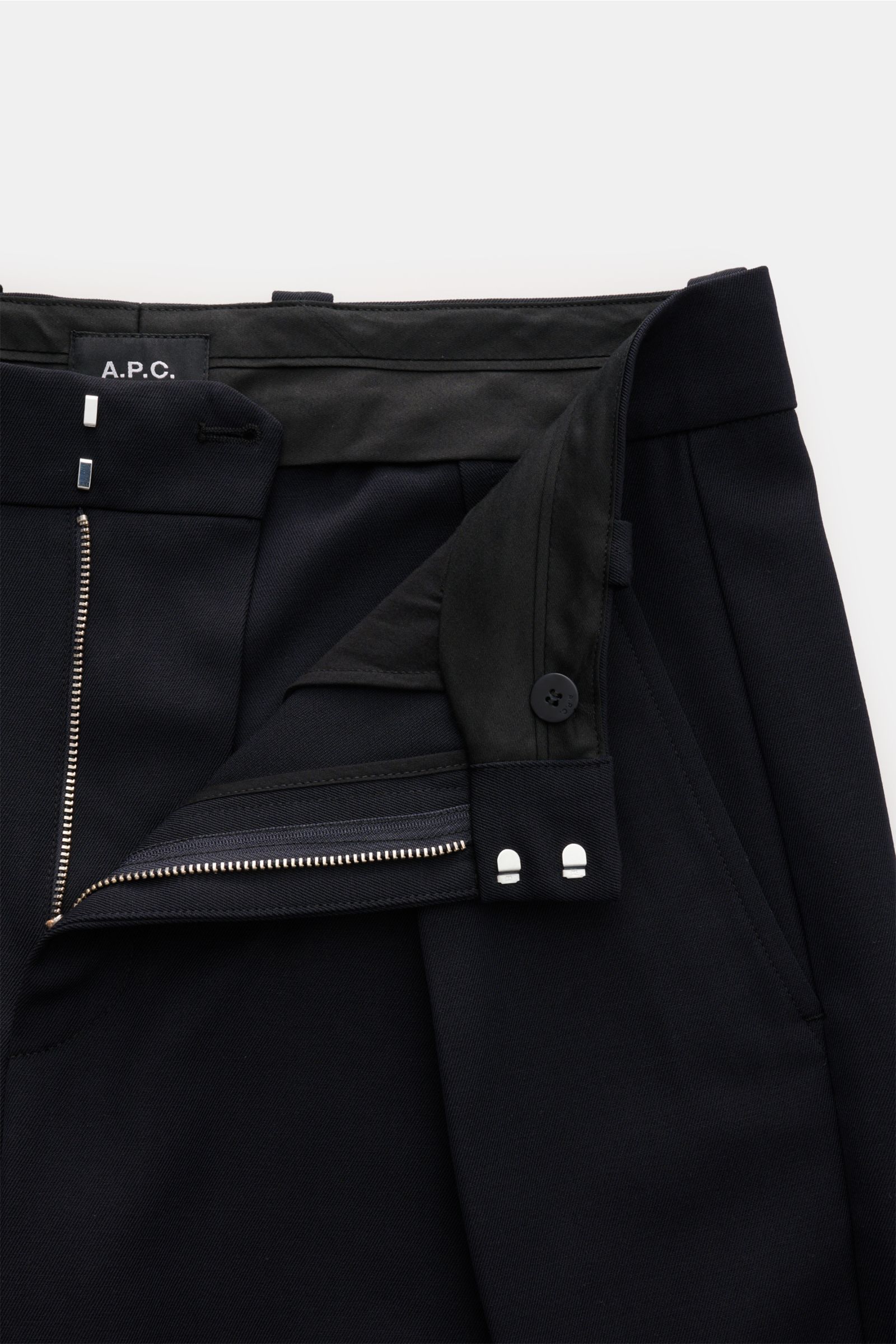 Close-up front view of A.P.C. Hose 'Renato' dark navy pants, showing zip fly, button, and waistband details. Stilvoller Klassiker: Die Hose 'Renato' von A.P.C. wird mit ihrem eleganten Design zum unverzichtbaren Essential in Ihrer Garderobe. Mix aus Wolle