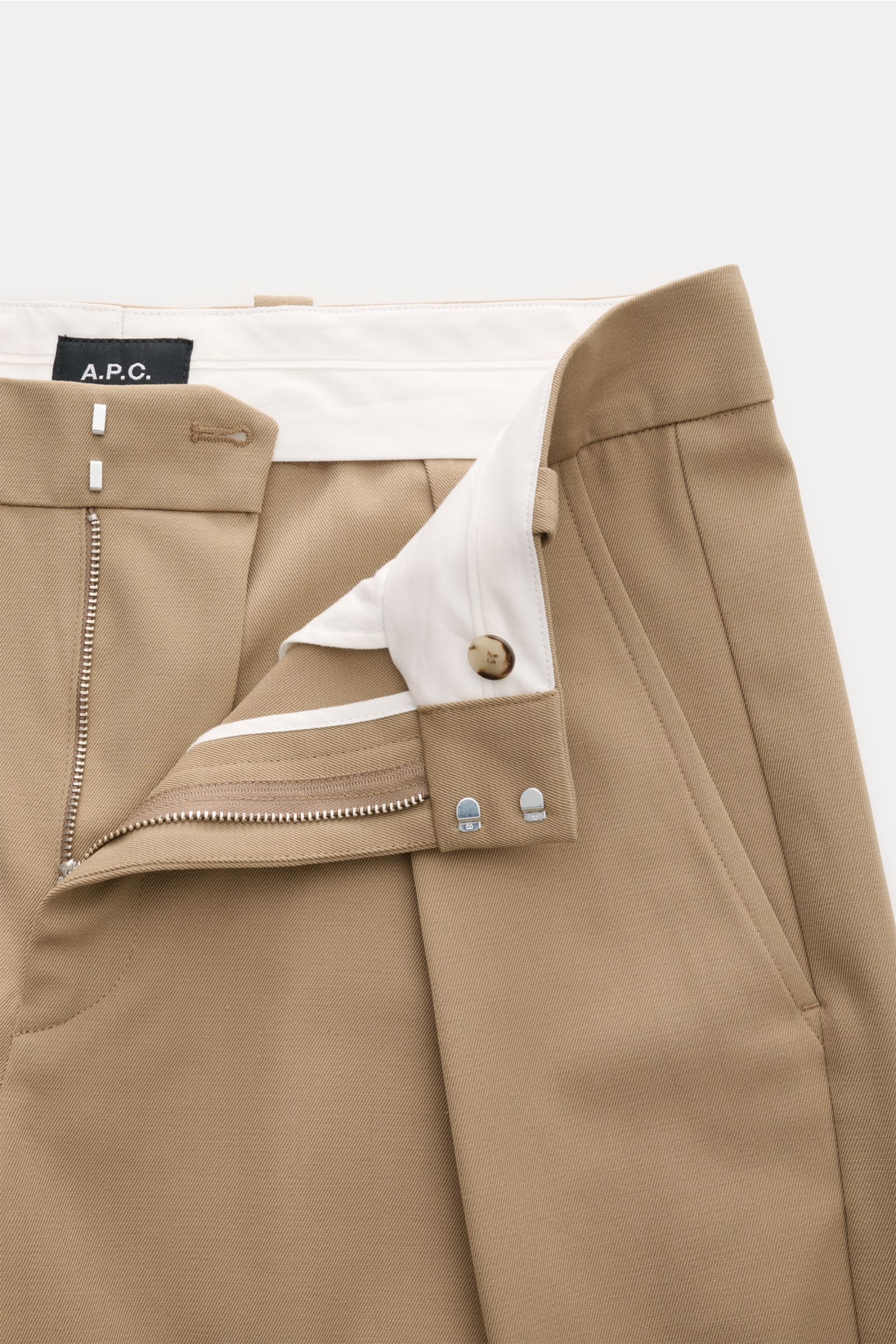 A close-up front view of the A.P.C. Hose 'Renato' camel pants with the zipper fly open, showing the high waistband, button, and hook closure. Stilvoller Klassiker: Die Hose 'Renato' von A.P.C. wird mit ihrem eleganten Design zum unverzichtbaren Essenti