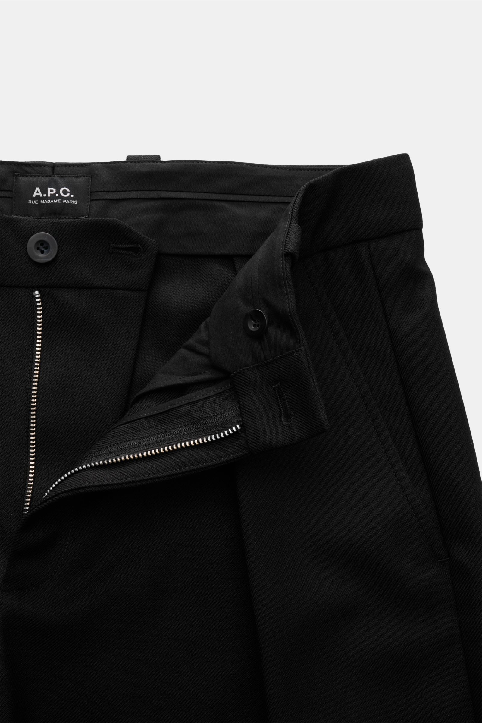 A close-up front view of A.P.C. Trousers 'Renato' black showing the high waist, zip fly, button closure, single pleat, and French pockets. Stylish classic: Trousers 'Renato' by A.P.C. have an elegant design that makes them an incomparable essential for yo