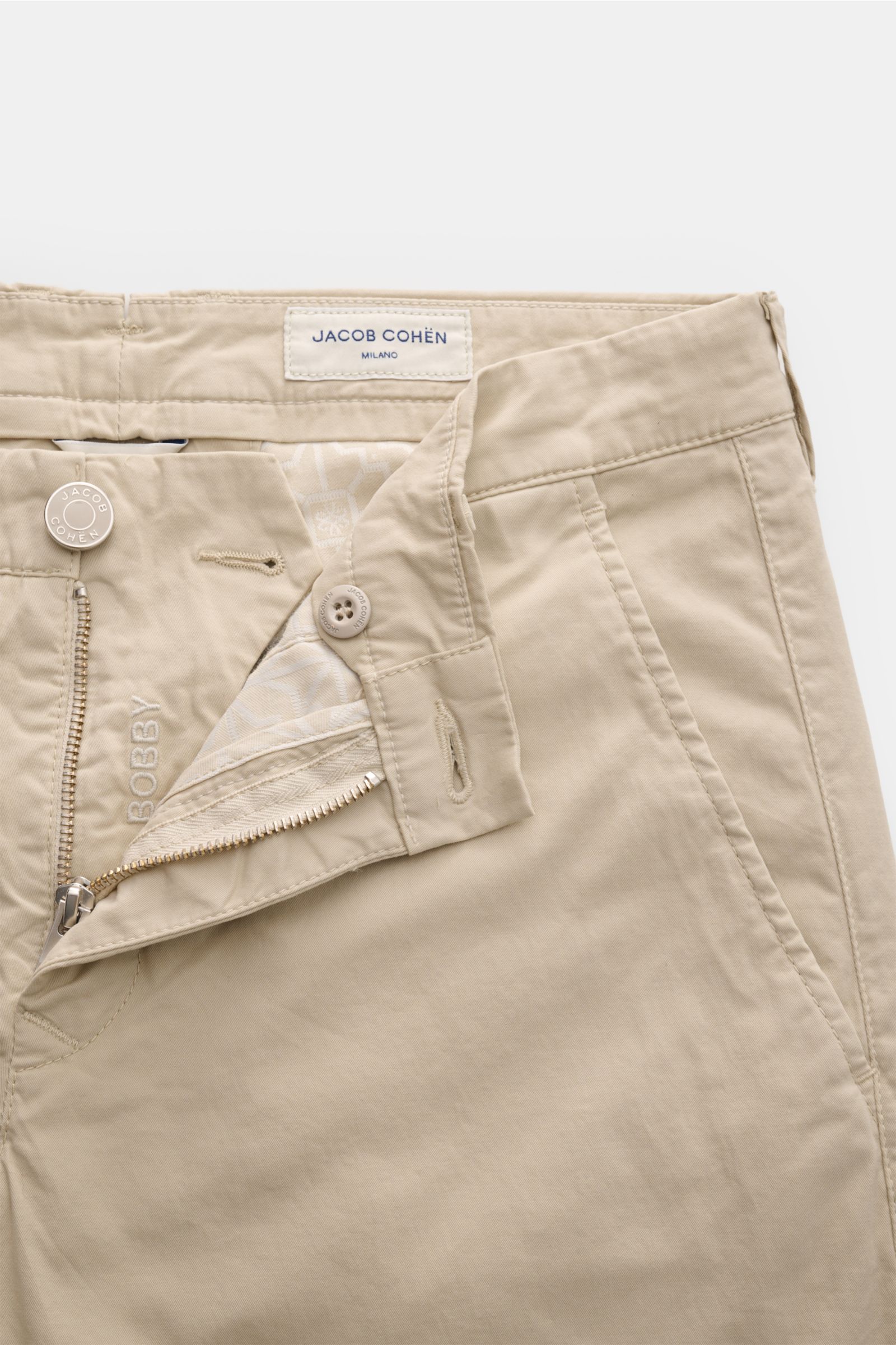 Jacob Cohen Chino 'Bobby' beige in schmalem Schnitt aus elastischem Baumwoll-Twill, frontal fotografiert mit offenem Reißverschluss.