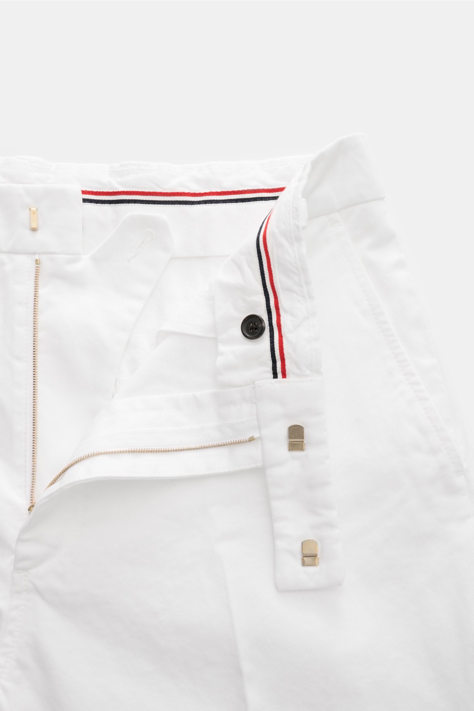 Thom Browne Chino weiß aus schwerem Baumwoll-Twill, Tapered Fit, knöchellang, mit Reißverschluss, Bundhaken, französischen Taschen, frontal fotografiert.