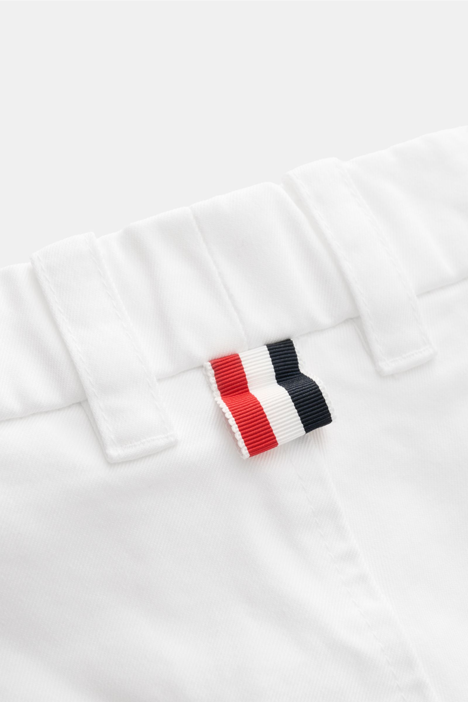 Thom Browne Chino weiß, Detailaufnahme des Taillenbunds mit Gürtelschlaufen und markantem rot-weiß-blauem Logo, Baumwoll-Twill.