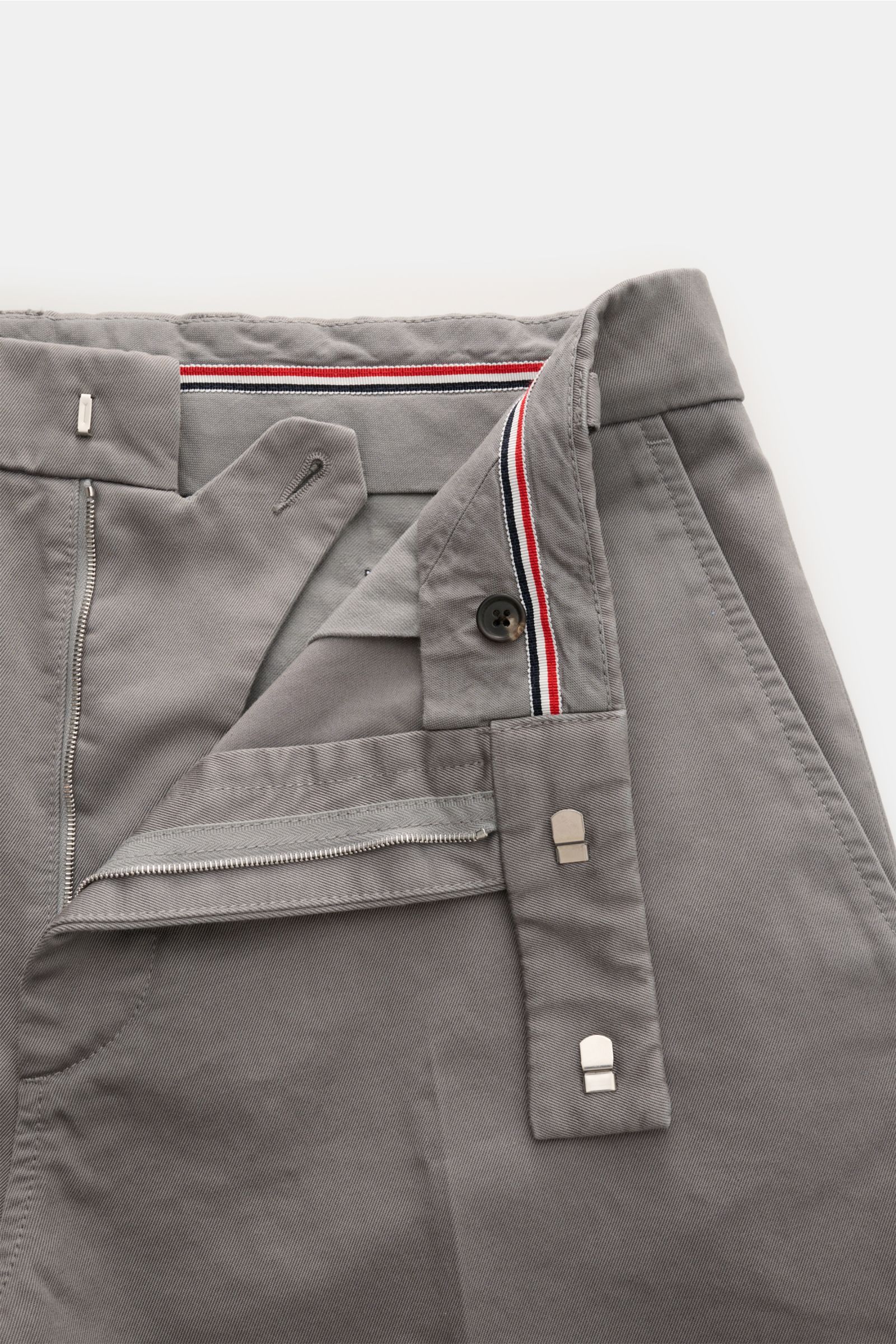 Nahaufnahme der geöffneten Thom Browne Chino grau aus schwerem Baumwoll-Twill, Tapered Fit mit Reißverschluss, Bundhaken und französischen Taschen.
