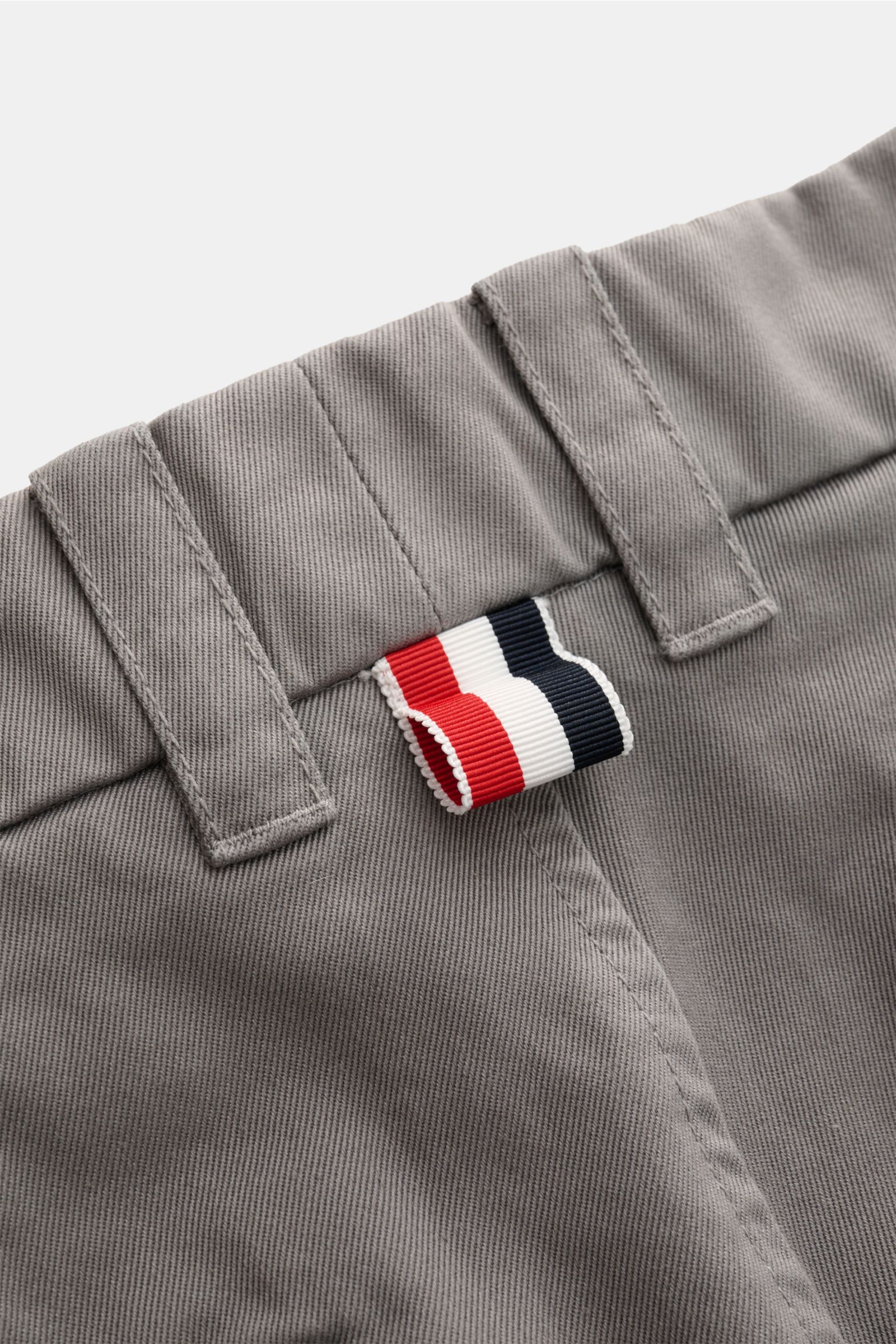 Nahaufnahme der Taille der Thom Browne Chino grau aus festem Baumwoll-Twill mit Tapered Fit, Gürtelösen und charakteristischem Tricolor-Label.