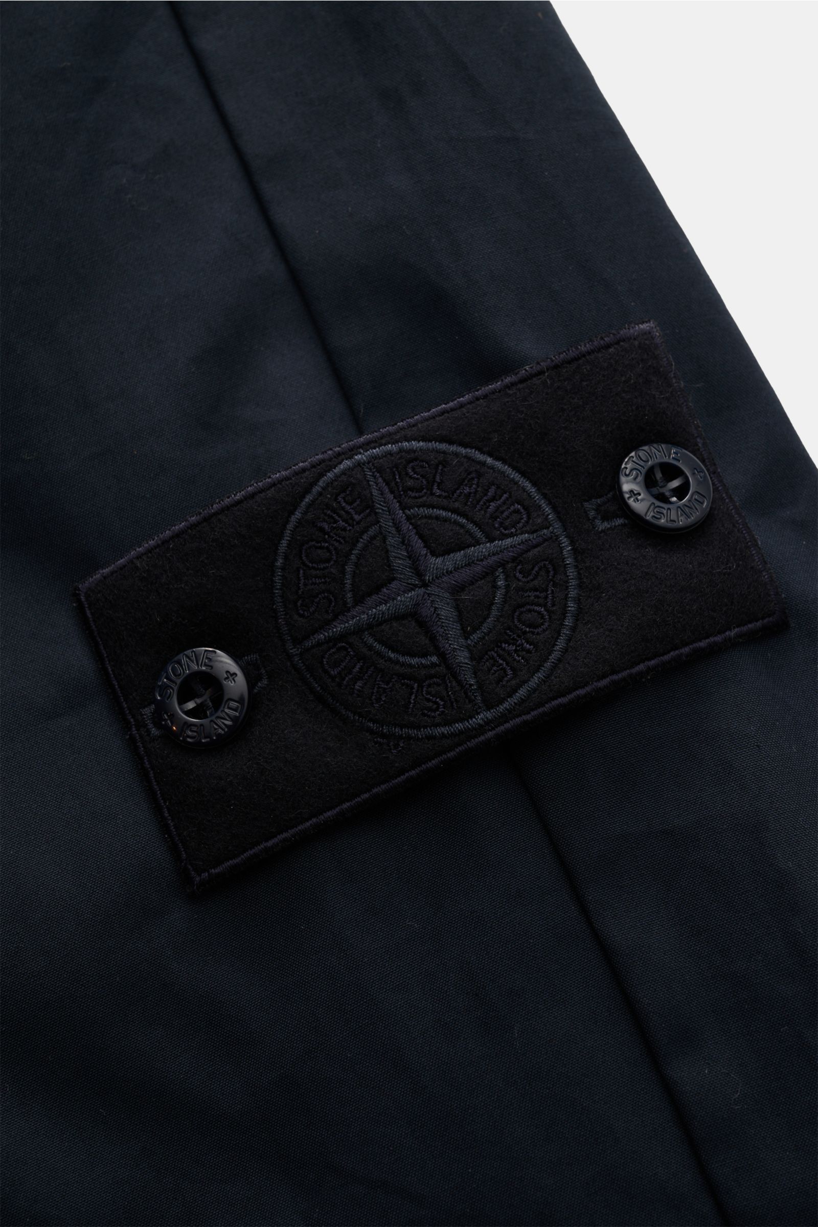 Stone Island Cargohose 'Ghost Piece' navy, Nahaufnahme des tonalen Kompass-Badges aus feinem Baumwoll-Twill, glatter Griff, garment dyed, frontal fotografiert.