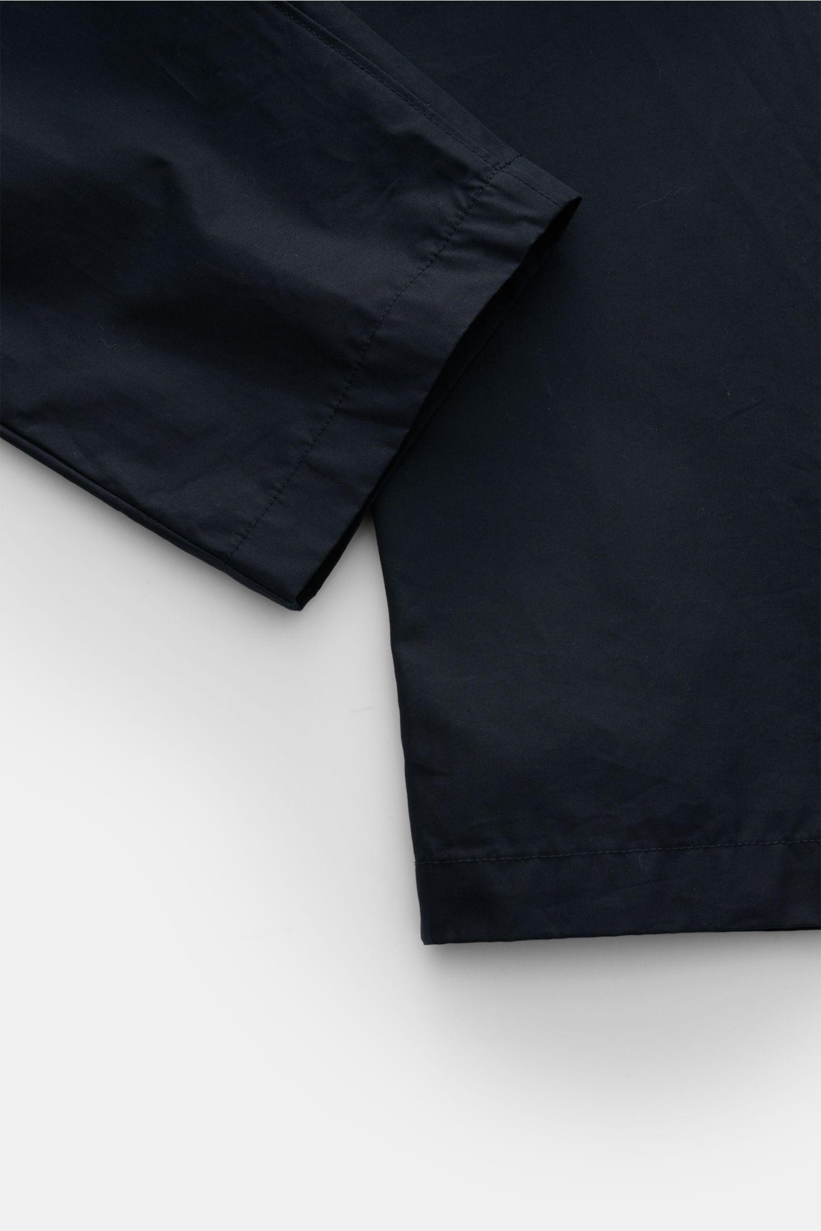 Stone Island Cargohose 'Ghost Piece' navy, knöchellang, Baumwoll-Twill, Tapered Fit, mit tonalem Kompass-Badge, Detailansicht Saum und Bein.