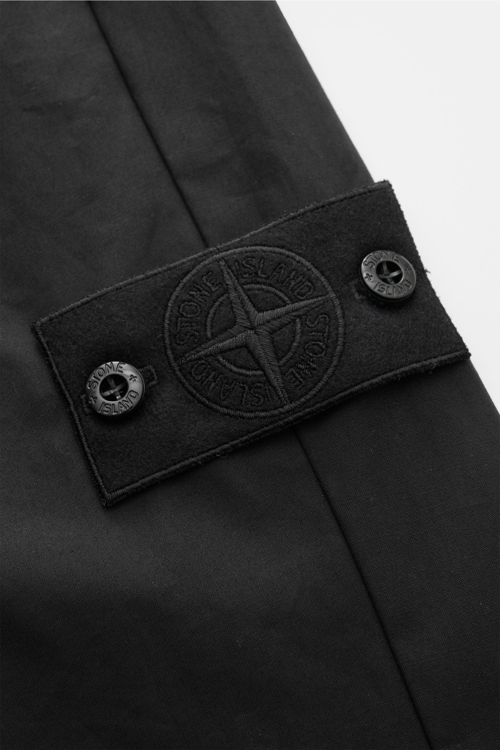 Stone Island Cargohose 'Ghost Piece' schwarz, Detailaufnahme des tonalen Kompass-Badges aus Baumwoll-Twill, glatter Griff, garment dyed.