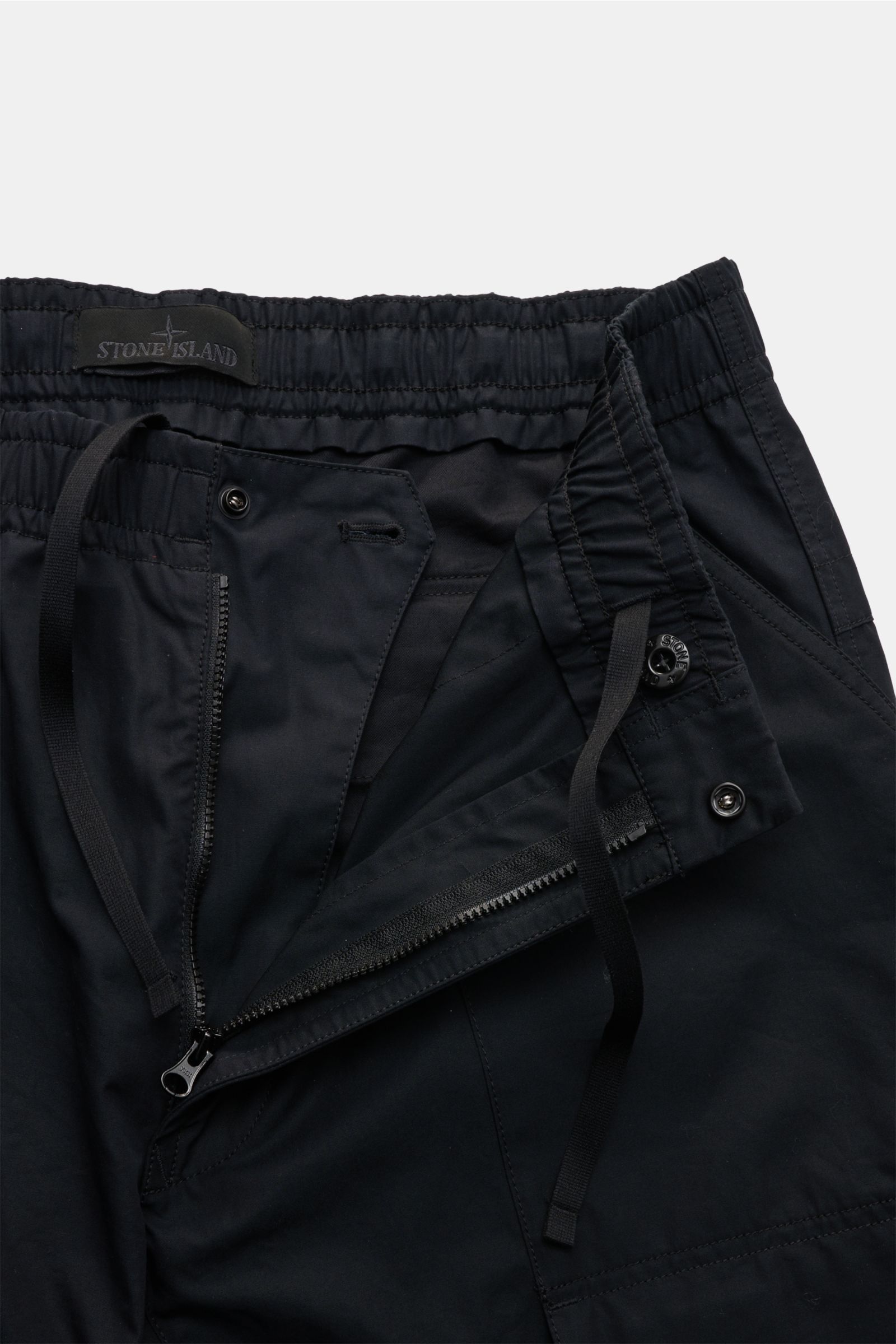 Stone Island Cargohose 'Ghost Piece' dark navy close-up from front top view showing elastic waistband, zipper, button, and tonal compass badge, made from garment-dyed cotton popeline with smooth texture, featuring loose fit, French pockets, typical cargo 