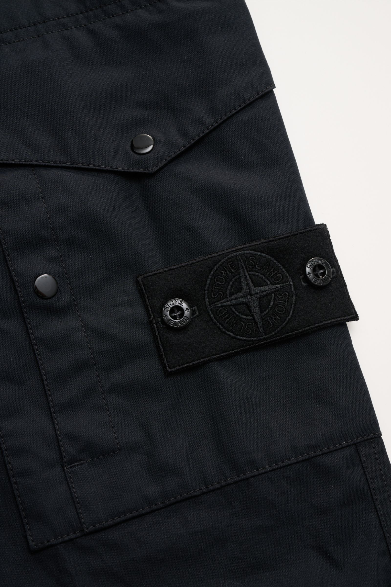 Close-up view of Stone Island Cargohose 'Ghost Piece' dark navy showing the tonal compass badge, snap buttons, and cotton poplin fabric details.

Description: Monochromer Allrounder für Casual-Looks: diese Cargohose aus robustem Baumwollpopeline von STONE