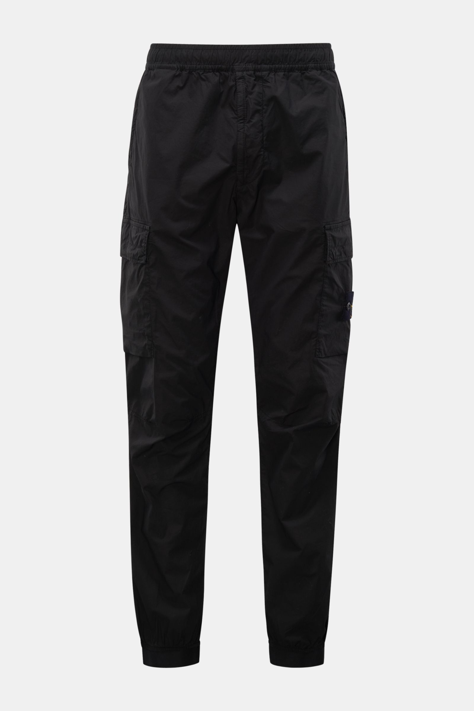 Front view of Stone Island Cargo-Jogpants 'Regular Tapered' schwarz in black cotton with stretch, featuring elastic waistband, zip pockets, cargo pockets, compass badge, knee darts, back button pocket, and elastic cuffs. For those who want function and st