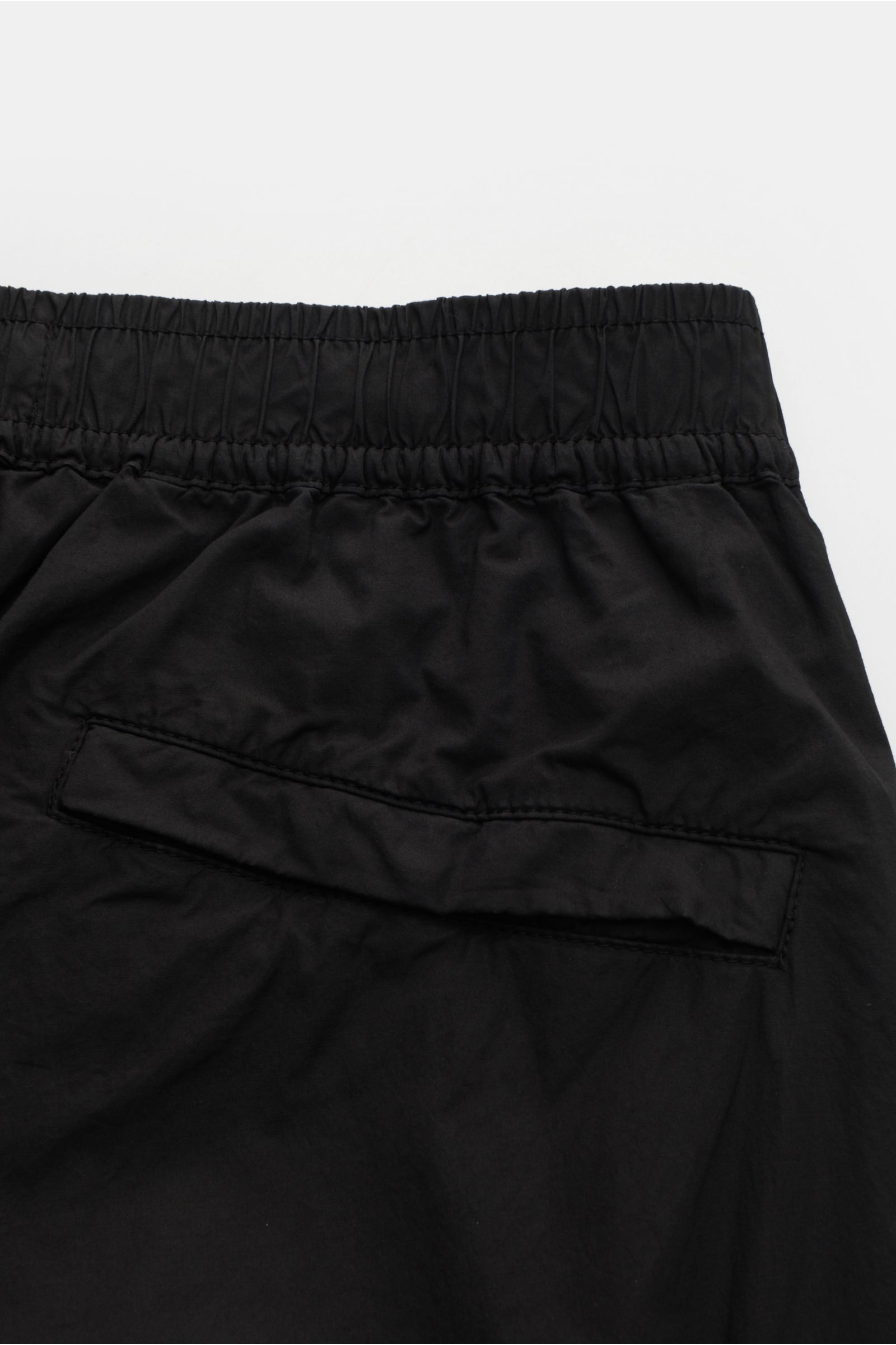 Close-up rear view of Stone Island Cargo-Jogpants 'Regular Tapered' schwarz, showing elastic waistband, back pocket with button, and soft black cotton fabric.