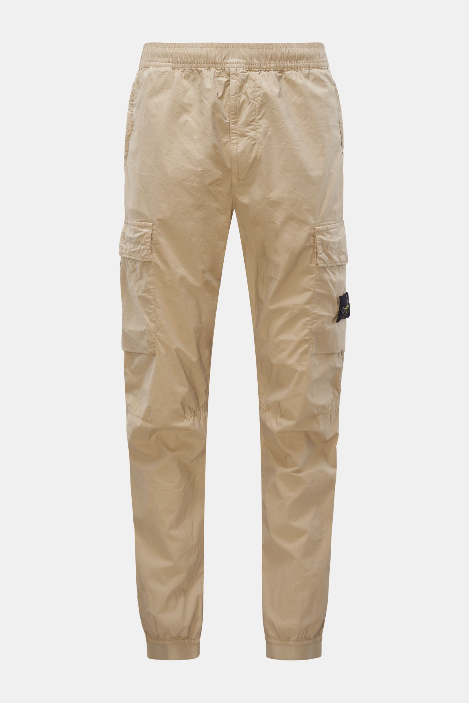 Stone Island Cargo-Jogpants 'Regular Tapered' beige, front view, elastic cotton with soft feel, tapered fit, short cut, elastic waistband, zip pockets, side seam and cargo pockets, compass badge, knee darts, buttoned back pocket, elastic cuffs. For those 