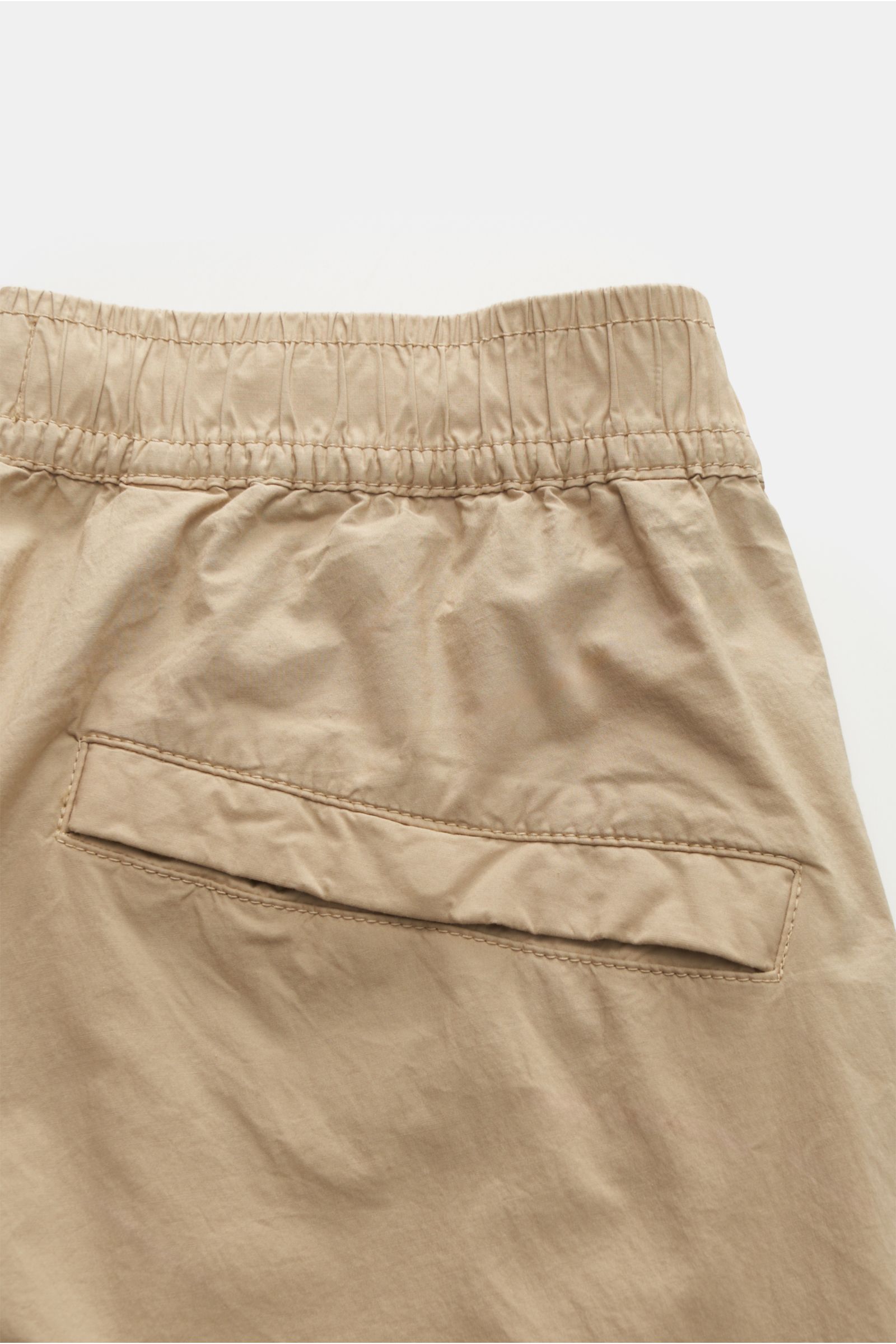 Close-up rear view of Stone Island Cargo-Jogpants 'Regular Tapered' beige, showing elastic waistband, back pocket with flap, and soft stretch cotton fabric. Für alle, die Funktion und Stil vereinen wollen – diese Cargo-Jogpants von STONE ISLAND ist inspir