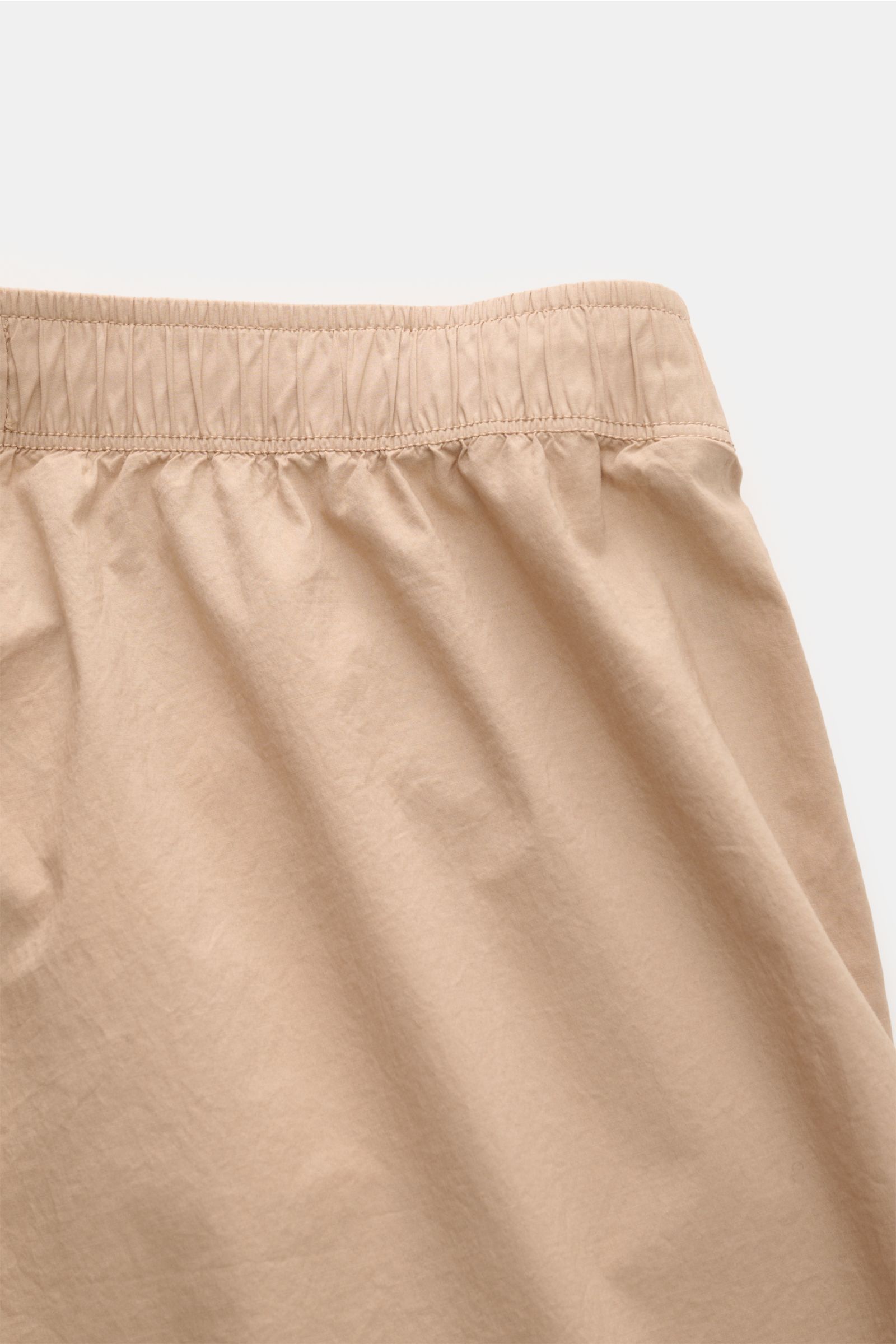 Stone Island Jogpants sand in Nahaufnahme von oben, elastischer Bund, glatte, elastische Baumwolle, lockerer Tapered Fit, labeltypisches Kompass-Badge.