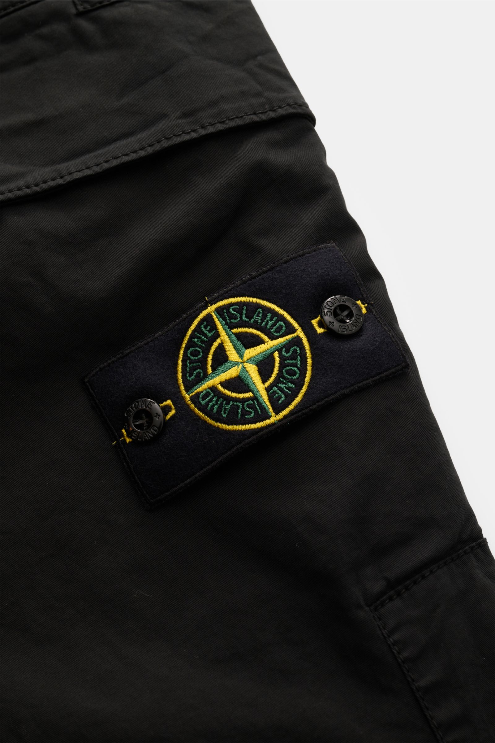 Stone Island Cargohose schwarz aus Baumwoll-Twill mit Kompass-Badge, schmaler Slim Fit, Abnäher und Cargo-Tasche, Nahaufnahme seitlich.