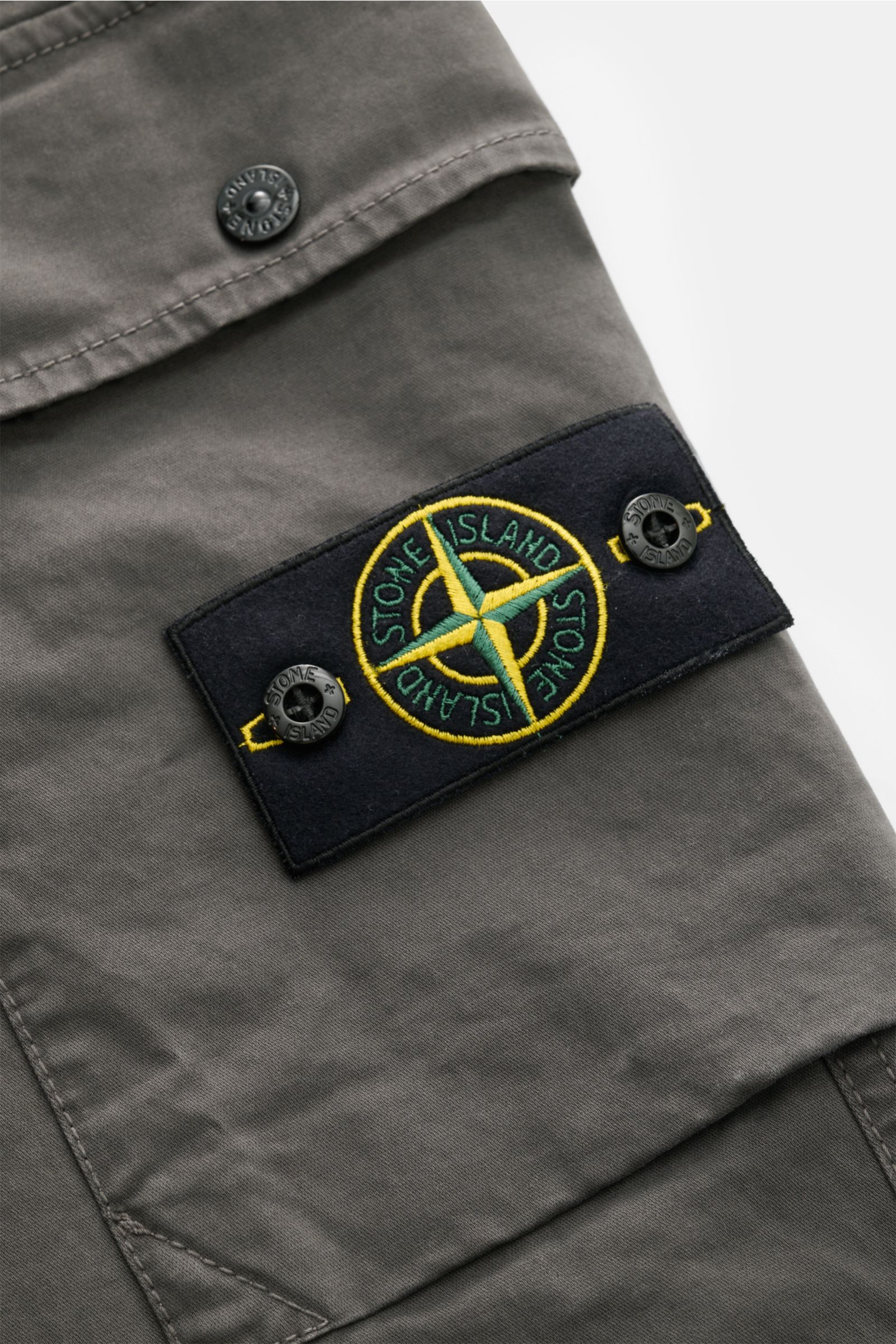 Stone Island Cargohose dunkelgrau, Detailaufnahme der aufgesetzten Cargotasche mit typischem Kompass-Badge aus elastischer Baumwolle.