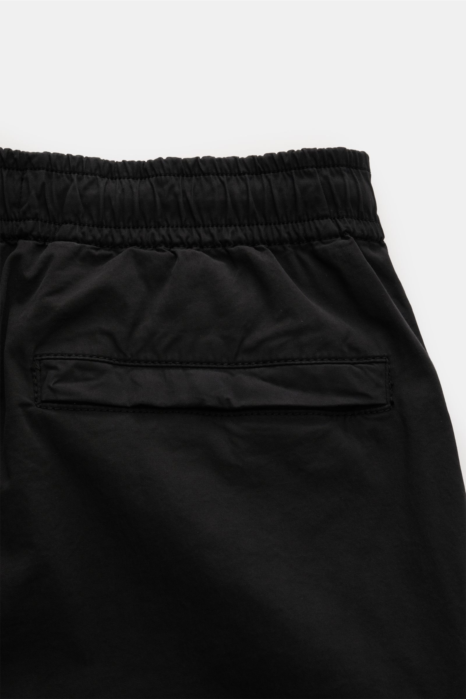 Black close-up of the back upper part of Stone Island Jogpants schwarz showing elastic waistband and back pocket with flap, photographed from above. Diese leger geschnittene Jogpants aus hochwertiger, leicht elastischer Baumwolle von STONE ISLAND hat m