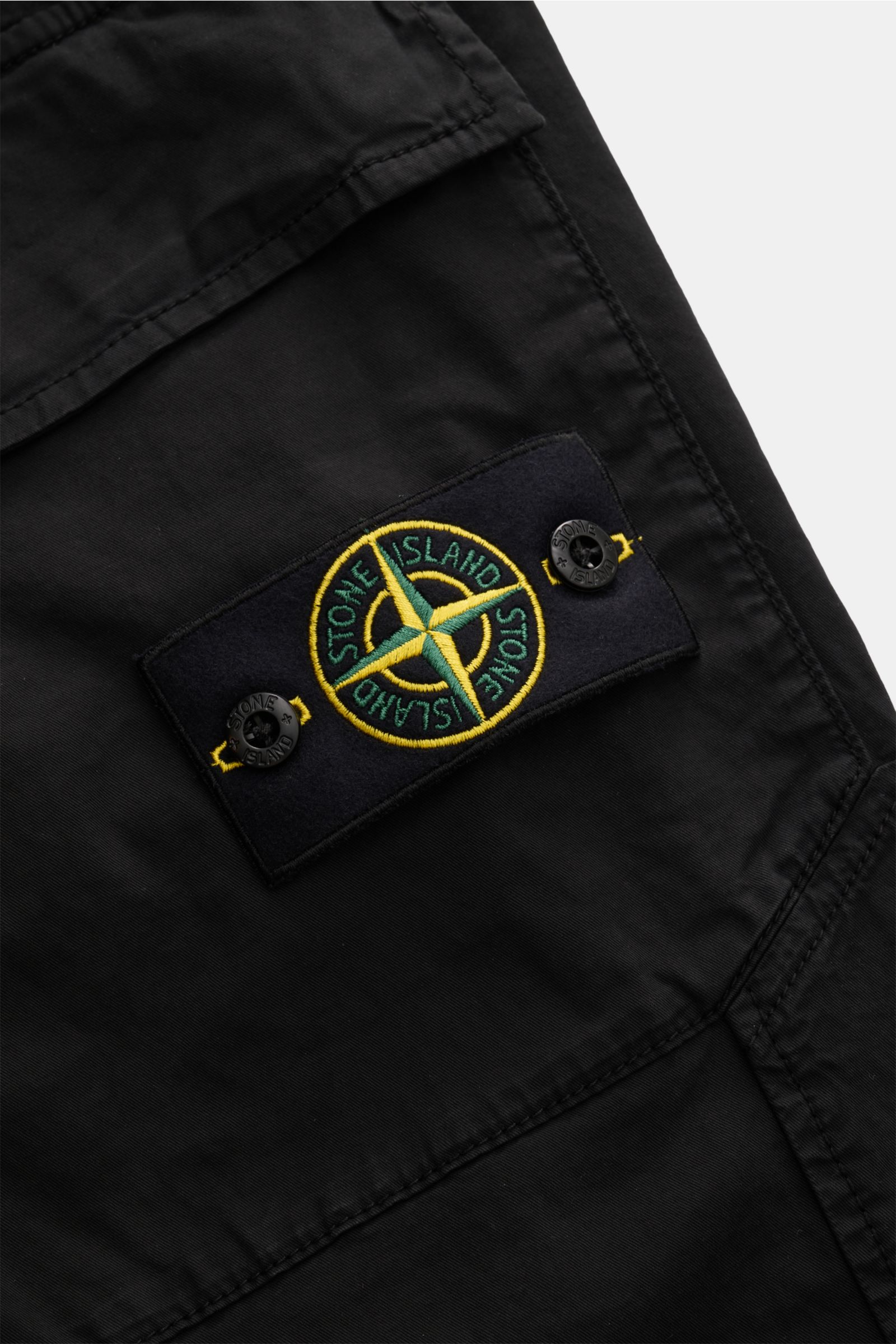 Stone Island Cargo-Jogpants schwarz, Detailaufnahme der aufgesetzten Tasche mit Kompass-Badge, leichte elastische Baumwolle, soft, garment dyed.