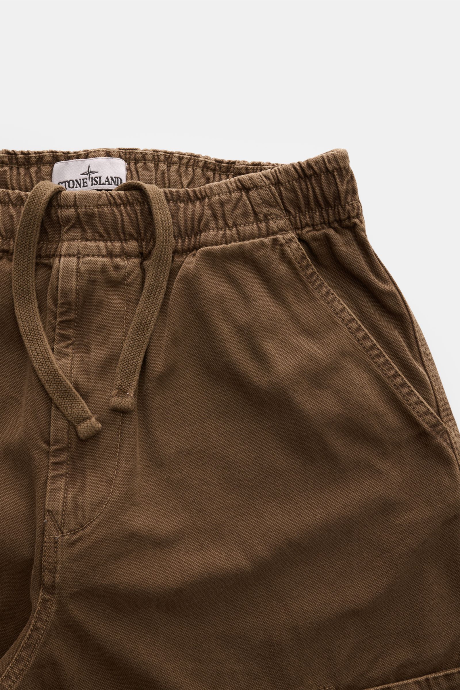 Nahaufnahme der Stone Island Cargo-Jogpants 'Panama' khaki aus stückgefärbter Bio-Baumwolle mit elastischem Bund, Tunnelzug und Taschen.