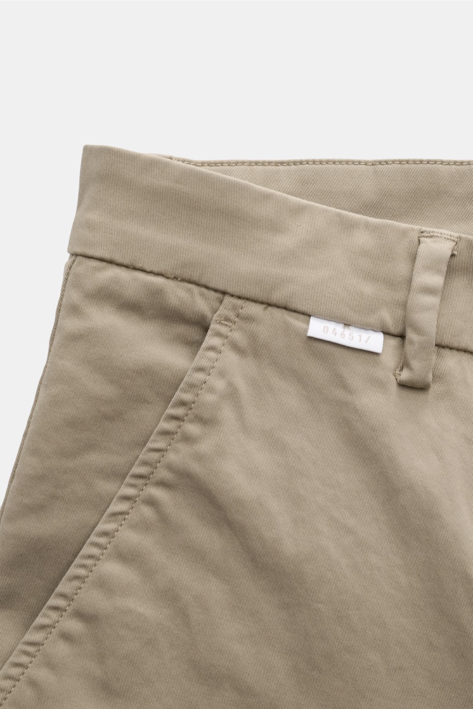 Nahaufnahme der Taille und Tasche der 04651/ A trip in a bag Chino taupe aus Baumwoll-Twill, leicht elastisch, Tapered Fit, knöchellang, mit Reißverschluss, Bundknopf, französischen Taschen und kleinem Weblabel.