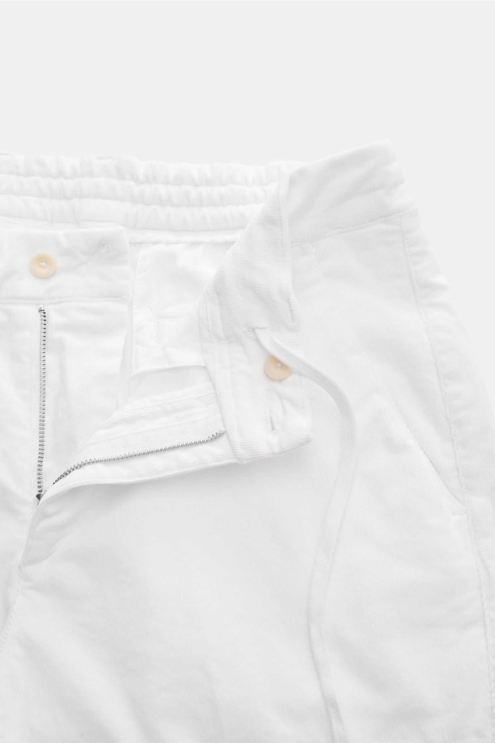 Close-up front view of 04651/ A trip in a bag Cordhose offwhite cotton cord pants with zipper, button, side-adjusters, and elastic waistband.