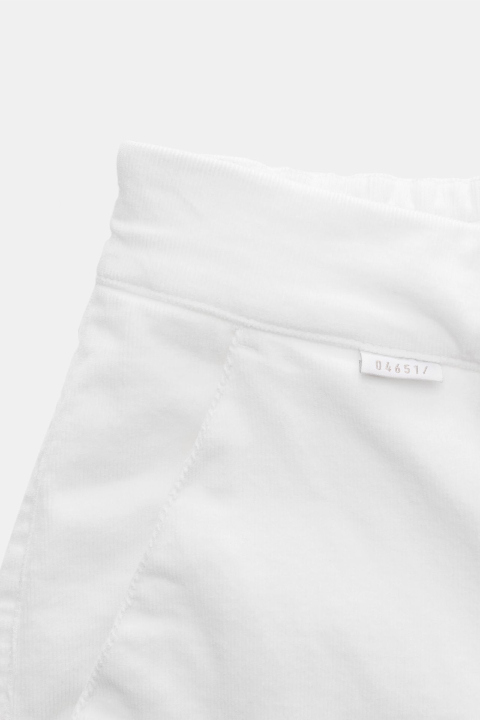Close-up front-side view of 04651/ A trip in a bag Cordhose offwhite made from soft, stretchy cotton cord with double waistband pleats and side-adjusters.