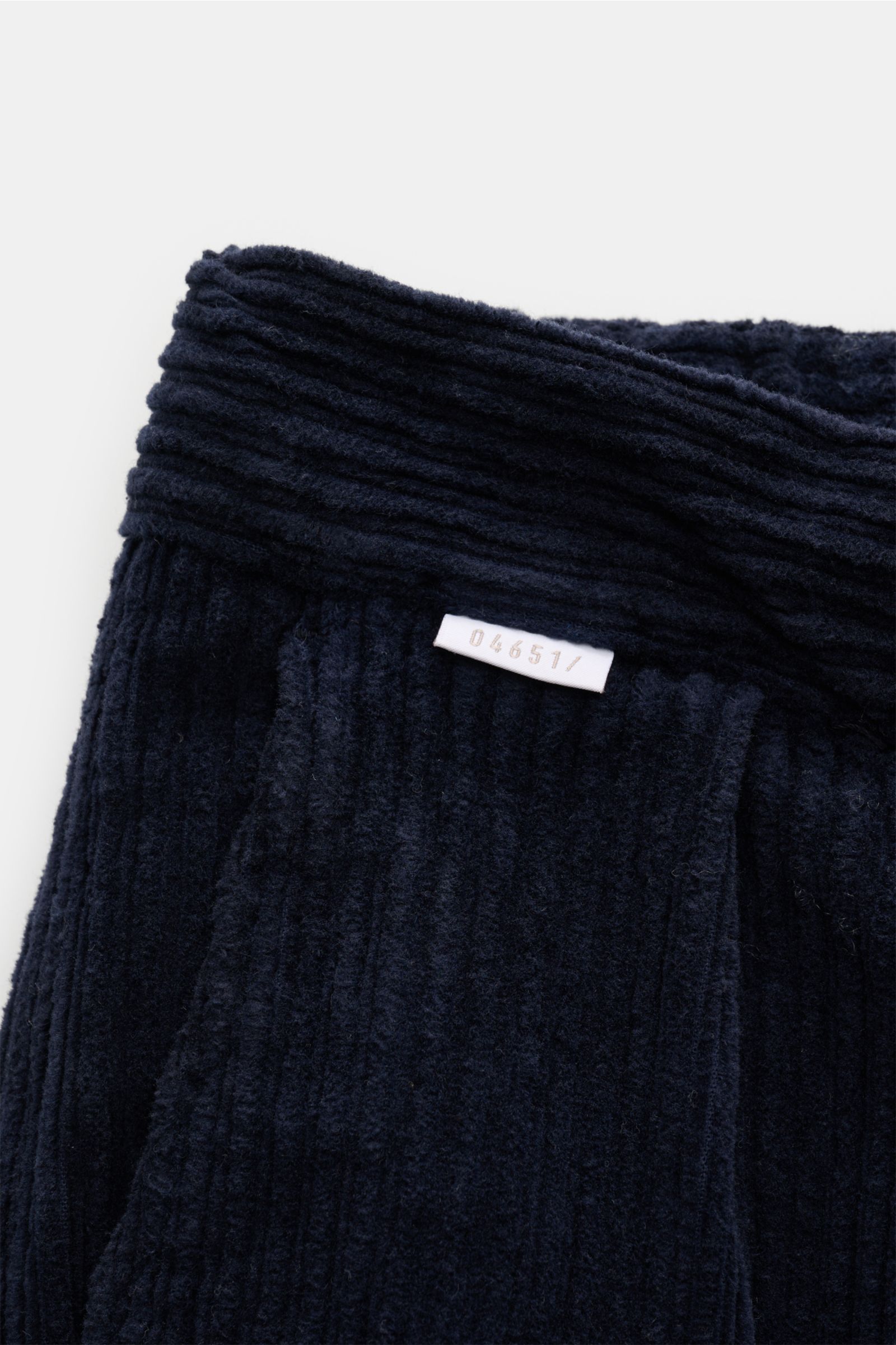 Close-up of the waistband of 04651/ A trip in a bag Corduroy cargo pants navy, showing wide wale cotton corduroy with a soft feel and small woven label, photographed from above. Features include slight stretch content, tapered fit with regular thigh width