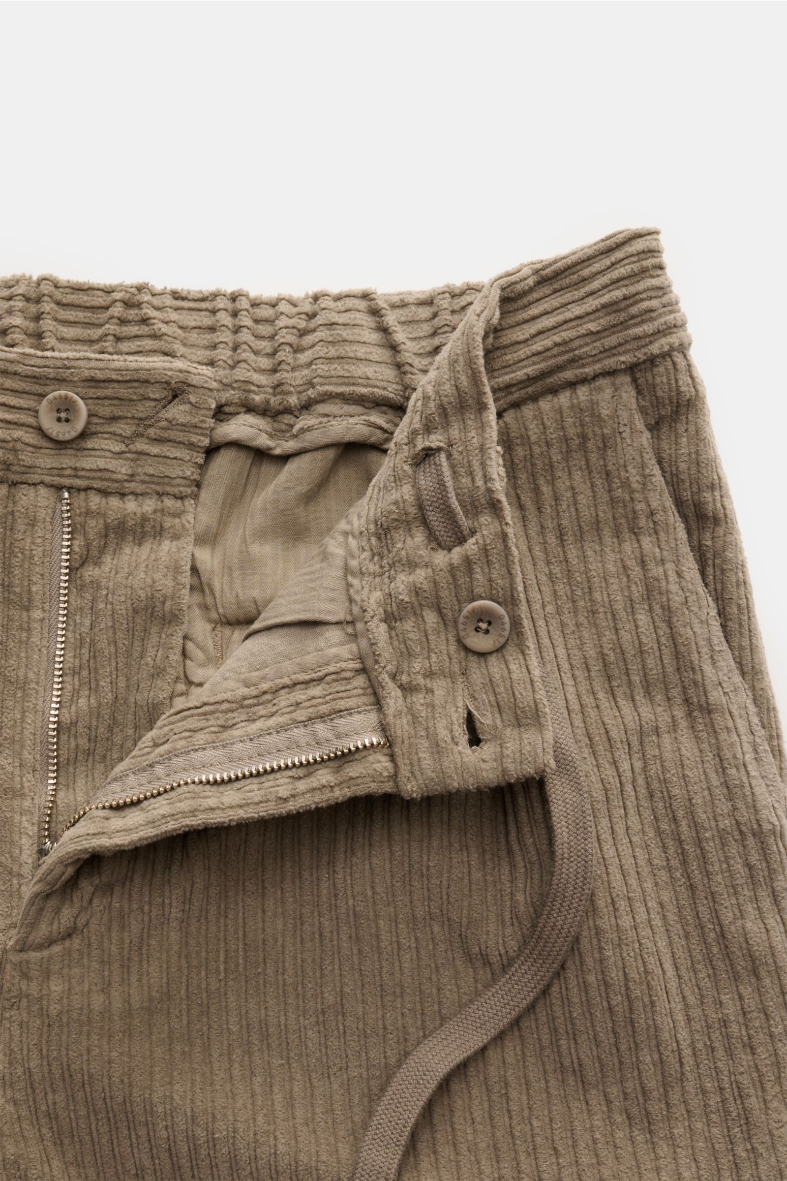 Close-up front view of 04651/ A trip in a bag Corduroy cargo pants taupe showing wide wale cotton corduroy, slight stretch, soft feel, zip and waist button, partially elasticated waistband with drawstring, French pockets, signature cargo pockets, small wo