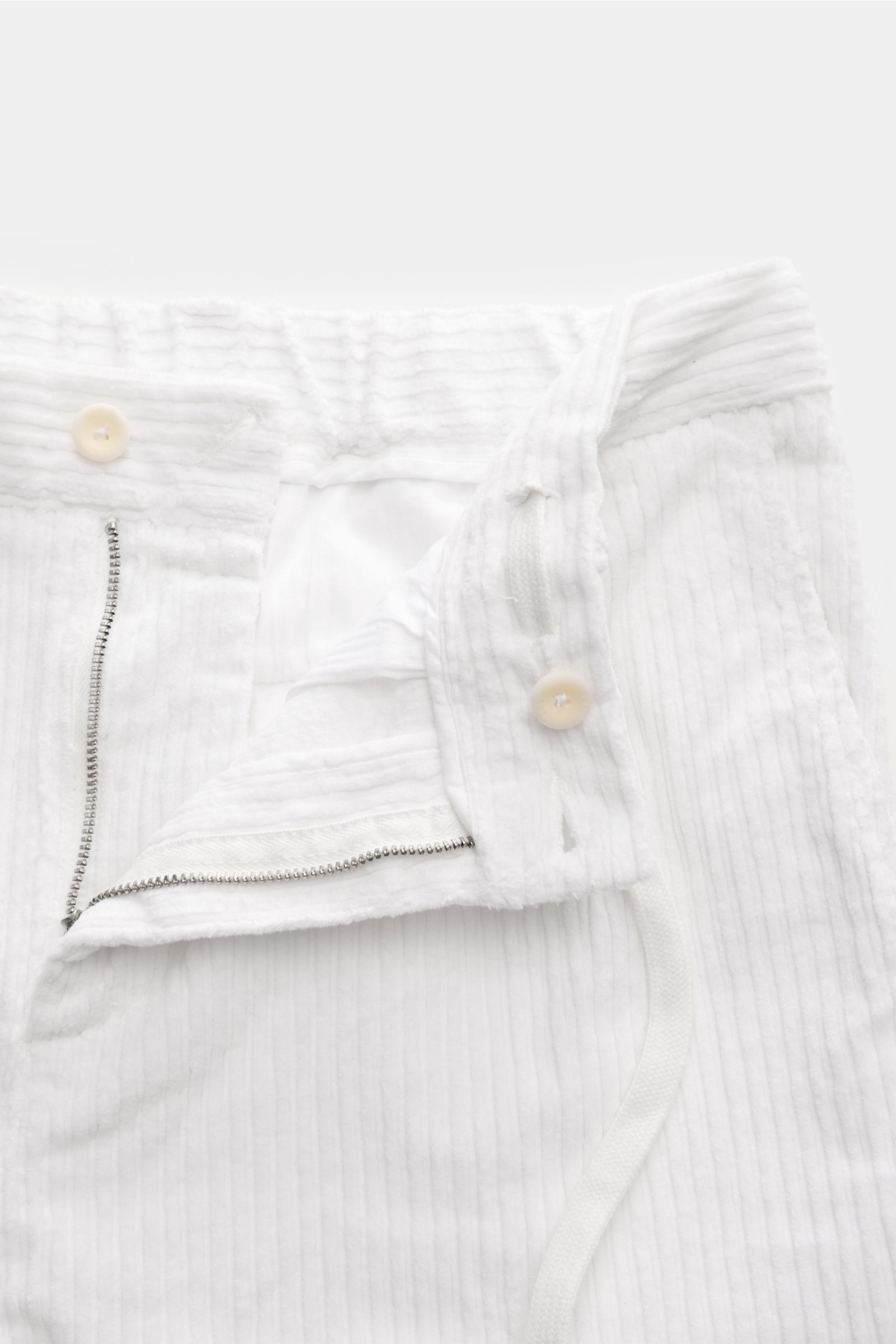 Close-up front view of 04651/ A trip in a bag Corduroy cargo pants off-white, showing wide wale cotton corduroy, zip and waist button, partially elasticated waistband with drawstring, soft feel, tapered fit, regular thigh width, ankle length, slightly tap