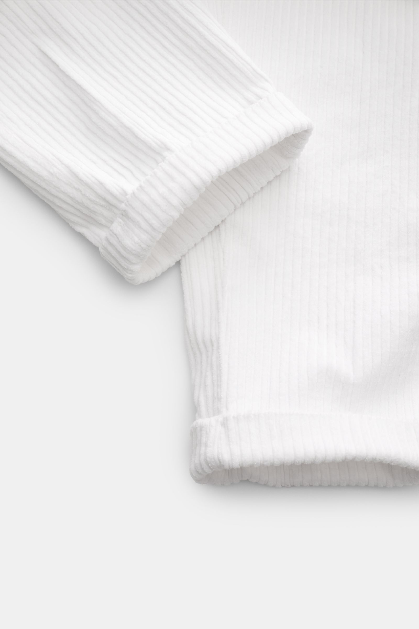 Close-up image from an angled top-down perspective showing the cuff and hem details of 04651/ A trip in a bag Corduroy cargo pants off-white, featuring wide wale cotton corduroy with slight stretch, soft feel, tapered fit, regular thigh width, ankle lengt