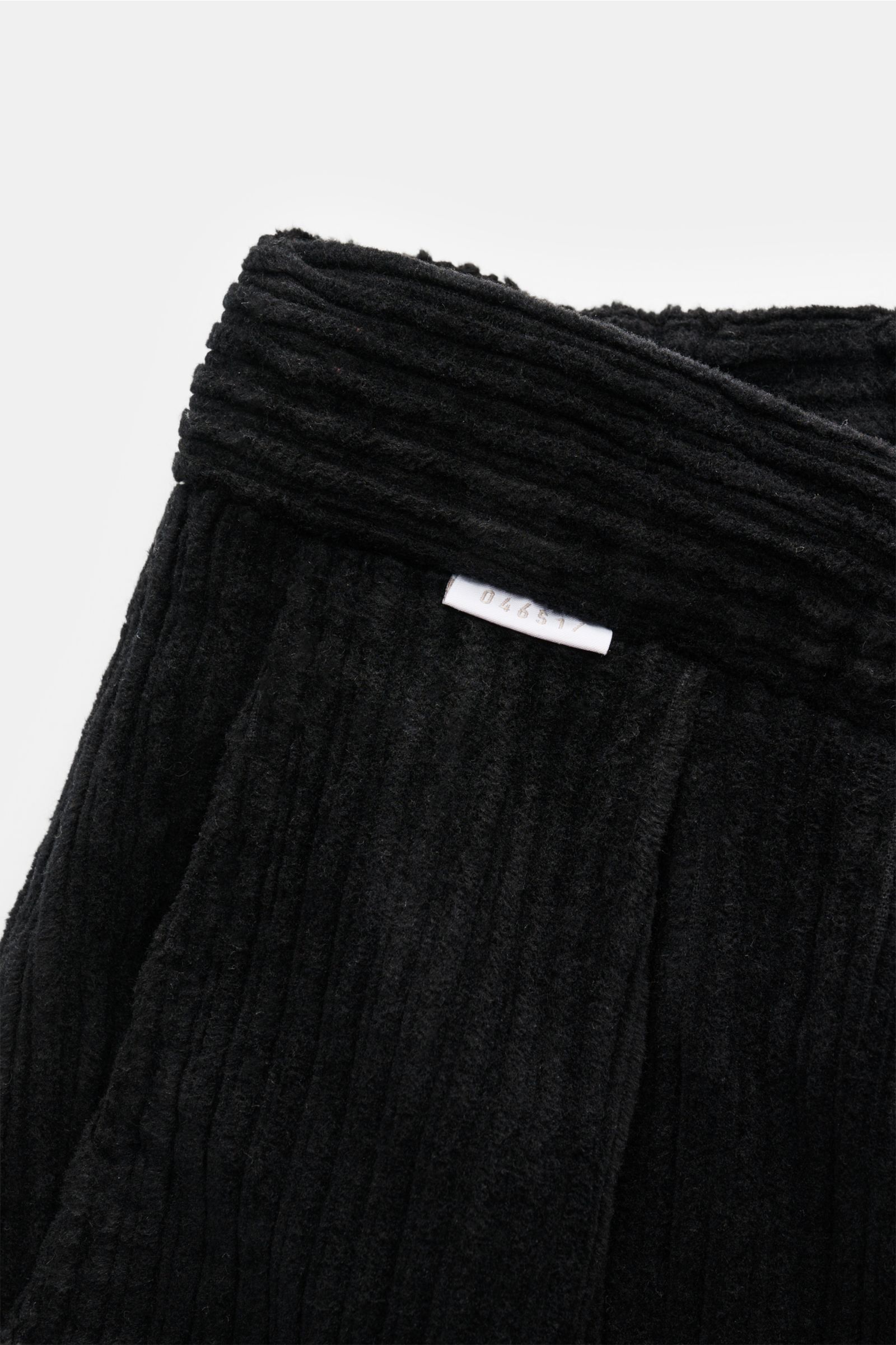 Close-up image of the waistband of the 04651/ A trip in a bag Corduroy cargo pants black, showing wide wale cotton corduroy with slight stretch, soft feel, tapered fit, regular thigh width, ankle length, slightly tapered cut, zip and waist button, partial
