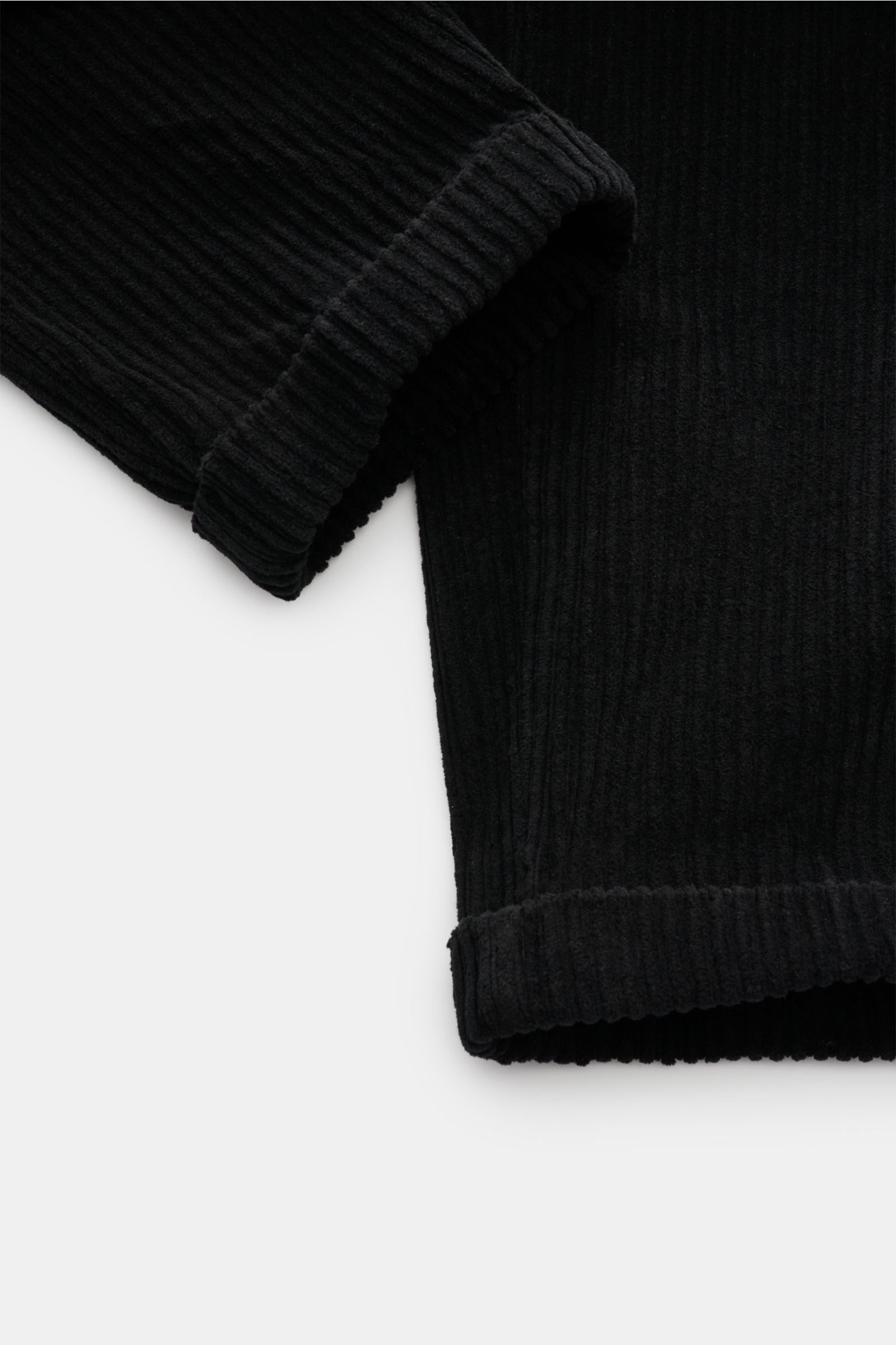 Close-up view of the lower legs of 04651/ A trip in a bag Corduroy cargo pants black, showing wide wale cotton corduroy fabric with slight stretch, soft feel, tapered fit, regular thigh width, ankle length, slightly tapered cut, fixed hem turn-up, and vis