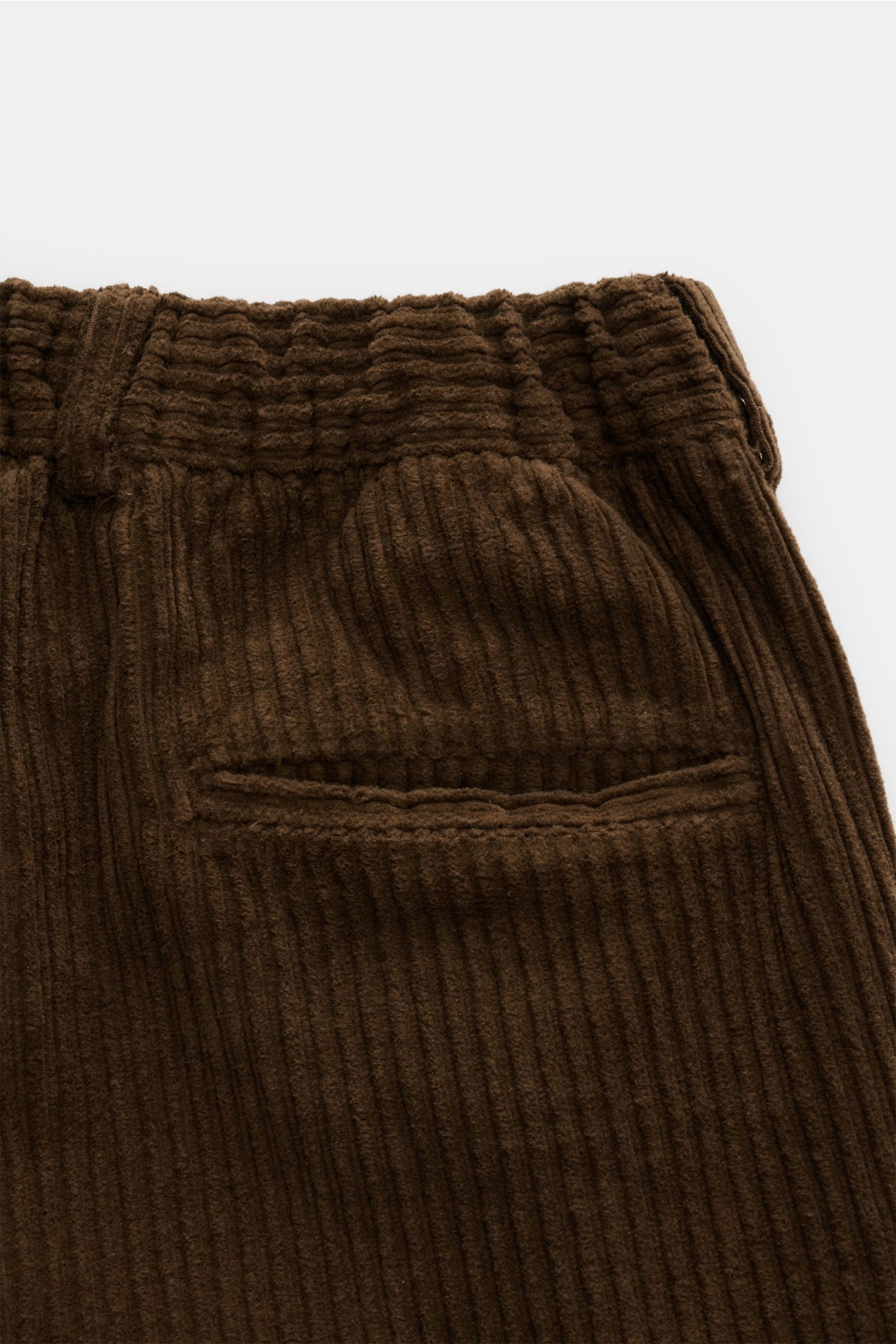 Close-up rear view of 04651/ A trip in a bag Corduroy cargo pants brown showing wide wale cotton corduroy, slight stretch, soft feel, tapered fit, regular thigh width, ankle length, slightly tapered cut, zip and waist button, partially elasticated waistba