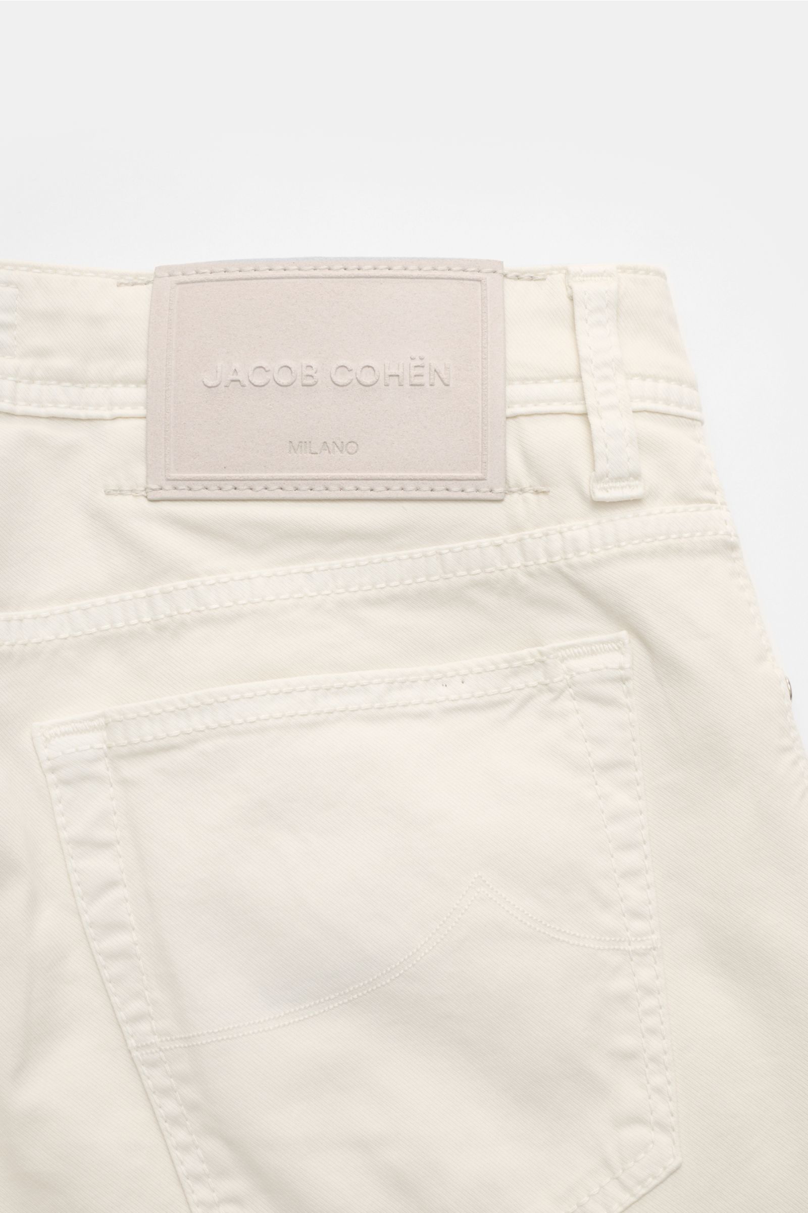 Close-up rear view of Jacob Cohen Trousers 'Bard' off-white, showing tonal stitching, back pocket, belt loop, and leather brand patch.

Get style and quality with the classic five-pocket trousers 'Bard' by JACOB COHEN in a slim fit. This luxurious and 